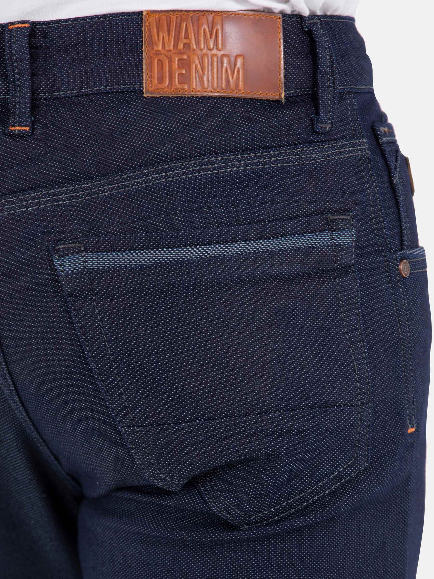Close-up of back pocket and leather waistband label on dark blue jeans – Wam Denim.