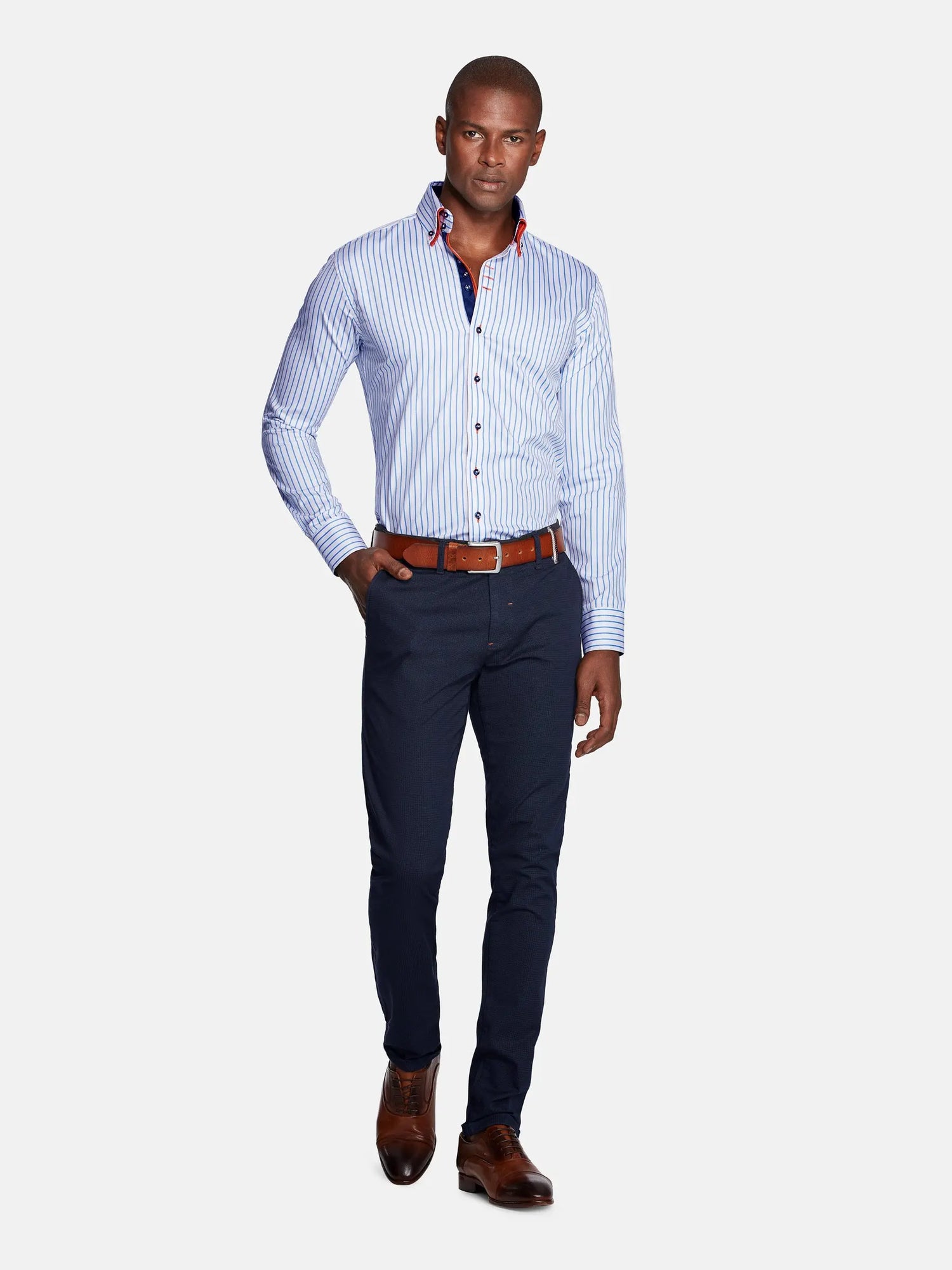 Model wearing navy slim-fit chinos paired with striped shirt and brown shoes – Wam Denim.