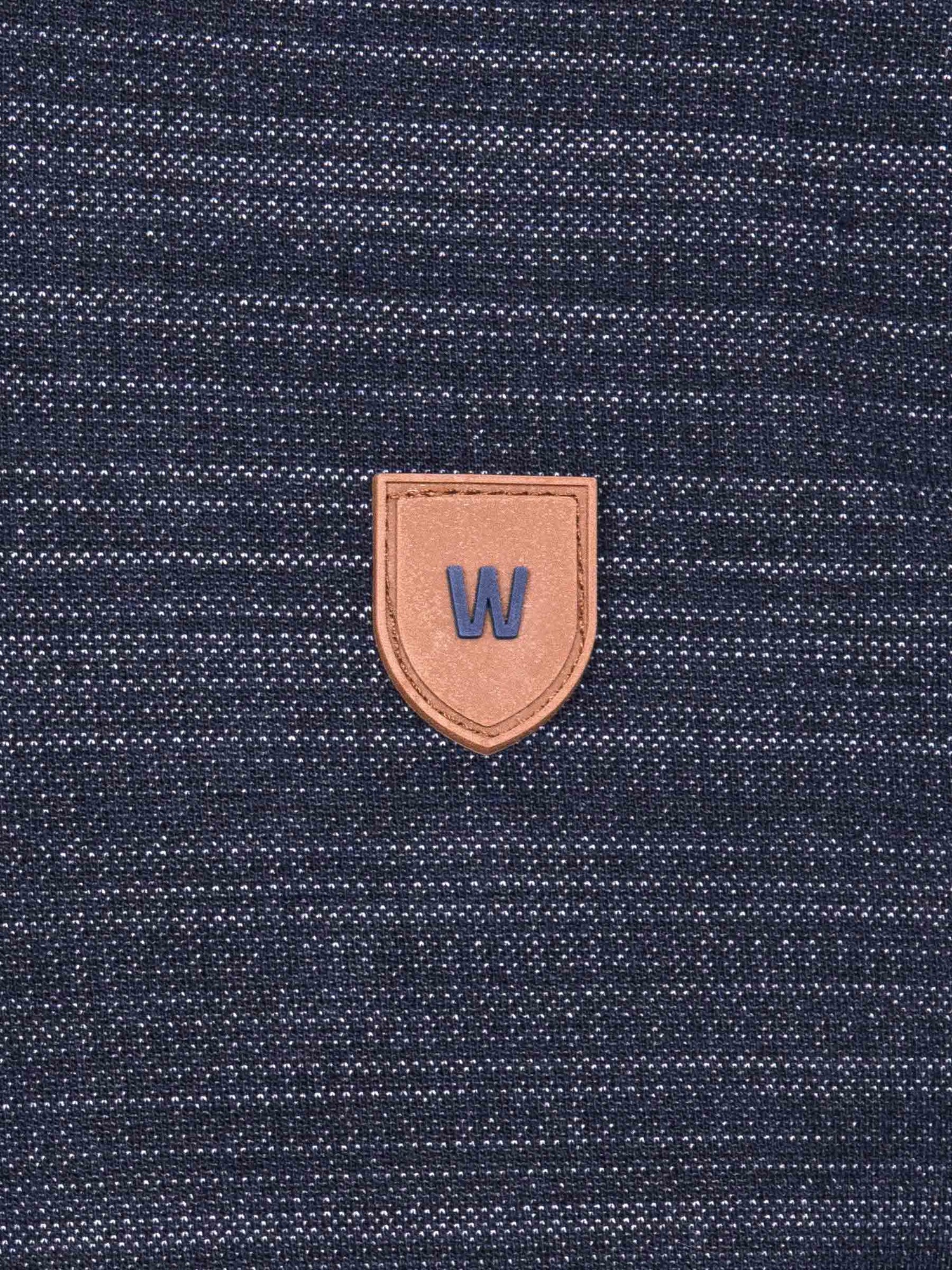 Close-up of a textured blue fabric with a brown leather patch featuring a 'W' logo.