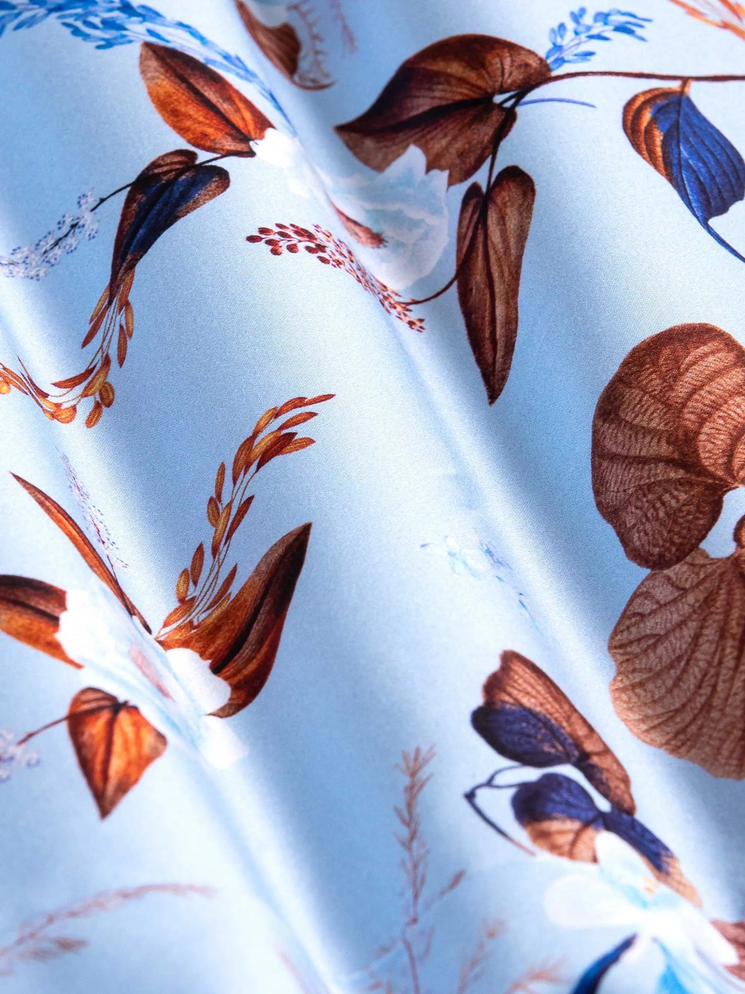 Close-up of light blue floral fabric with brown and navy leaf patterns – Wam Denim.