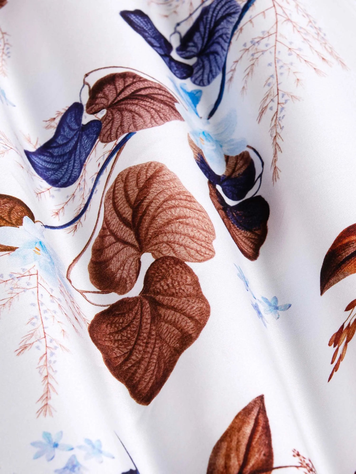 Close-up of white floral fabric with brown and blue leaf pattern – Wam Denim.