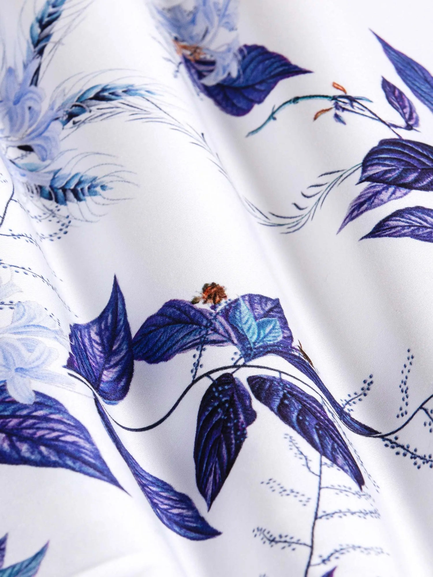 Close-up of white fabric with blue floral and leaf print texture showing fine details – Wam Denim.