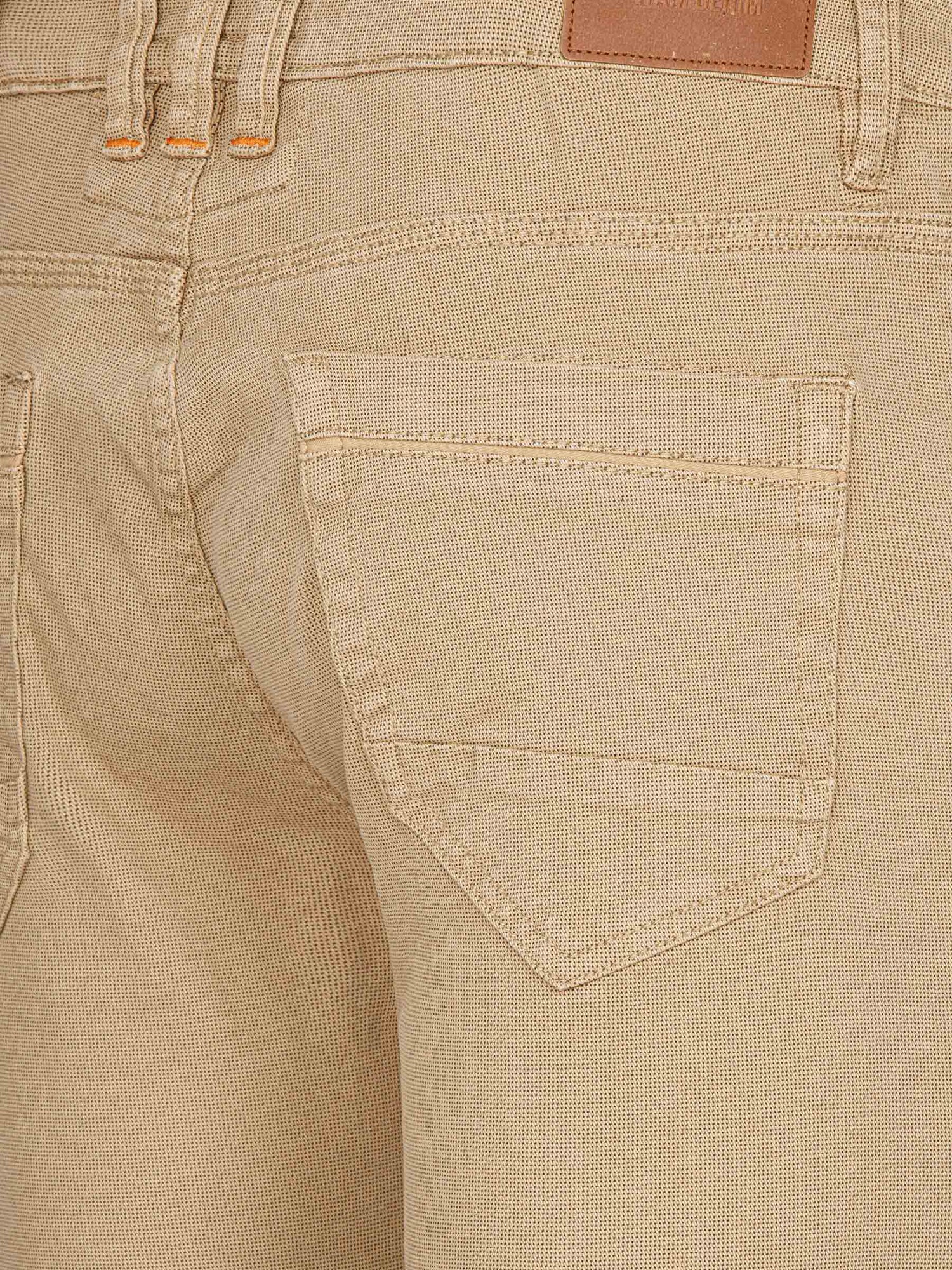 Close-up of the back pocket on beige men's cotton jeans – Wam Denim.