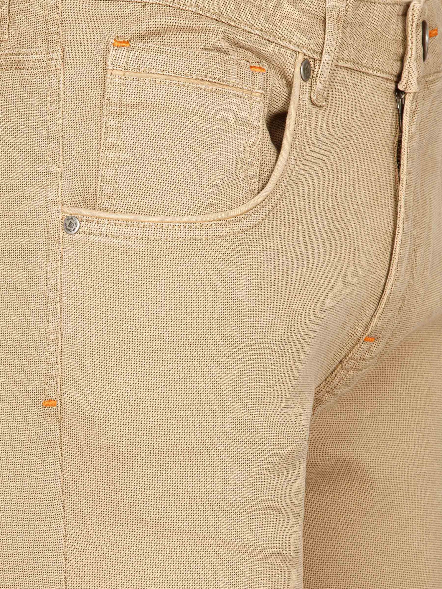 Close-up of beige denim pants with orange stitching and pocket. – Wam Denim.