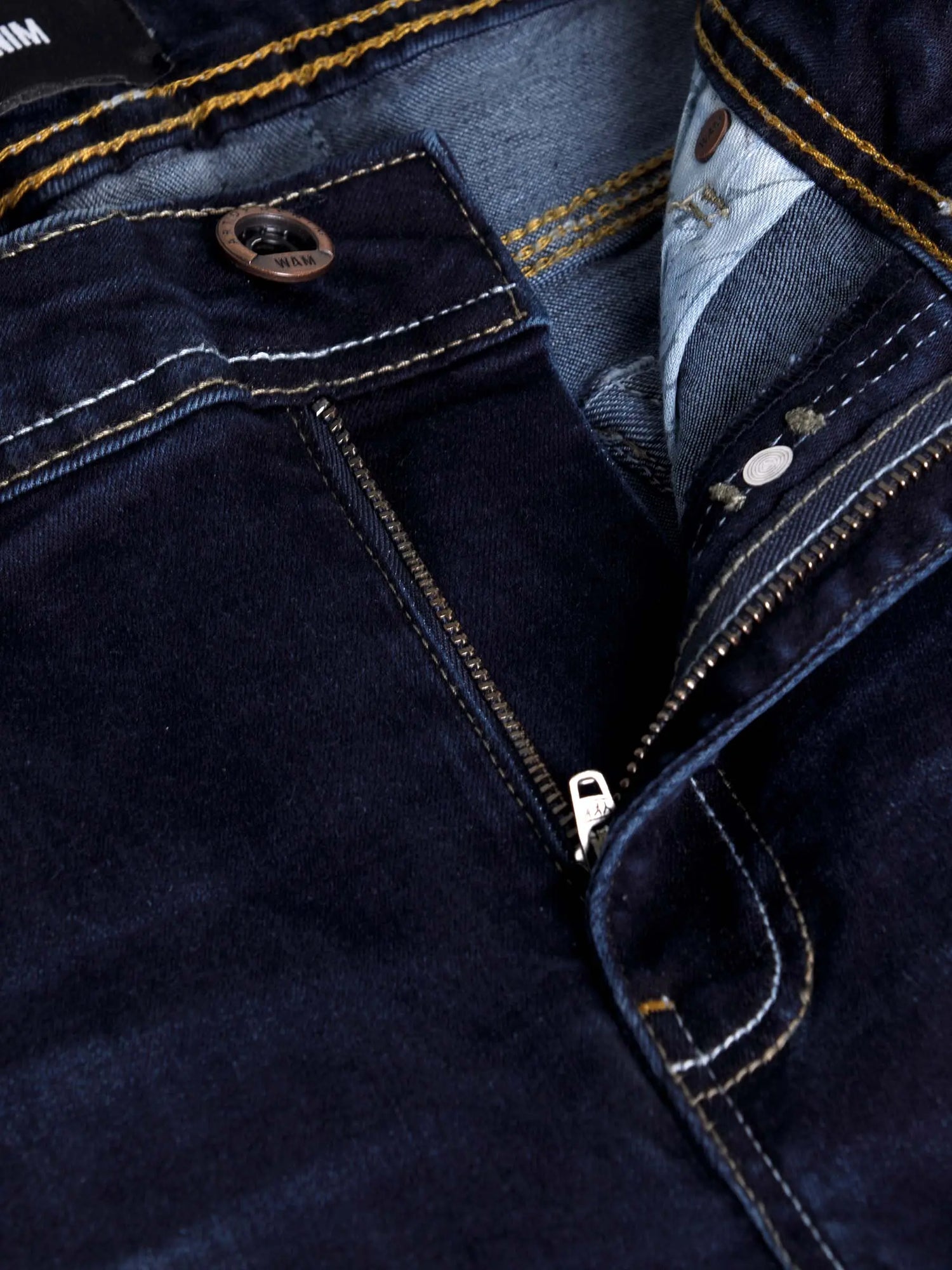 Close-up of dark navy denim jeans zipper and button detail with contrast stitching – Wam Denim.