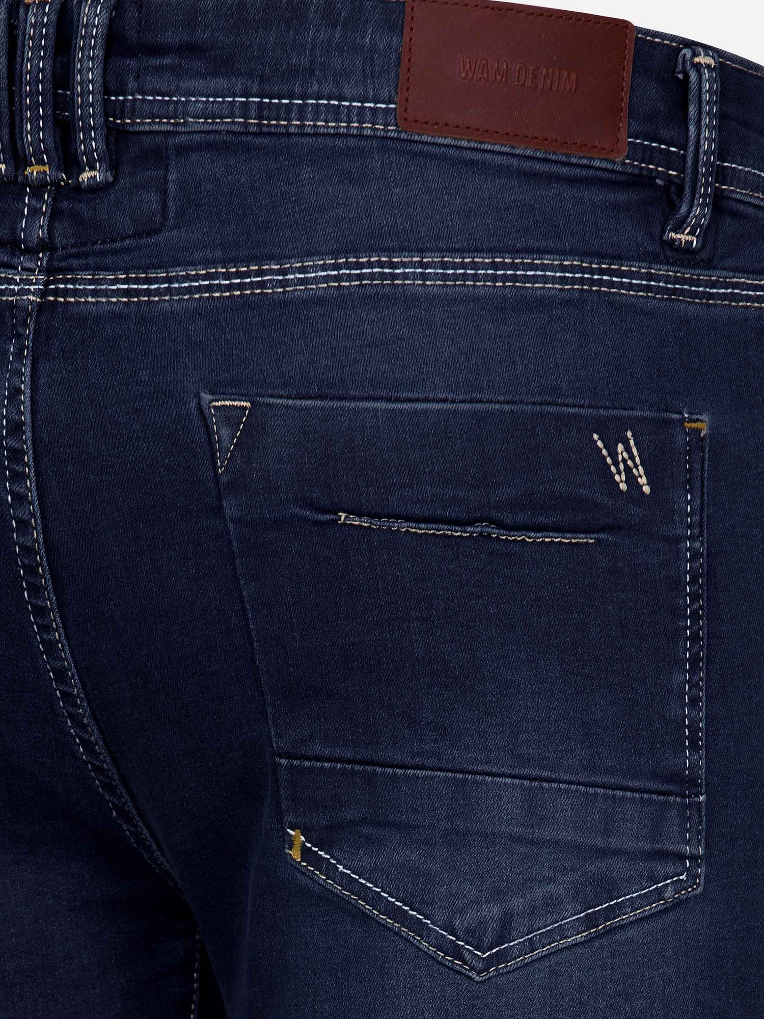 Back pocket close-up of dark navy jeans with stitched “W” logo and leather patch – Wam Denim.
