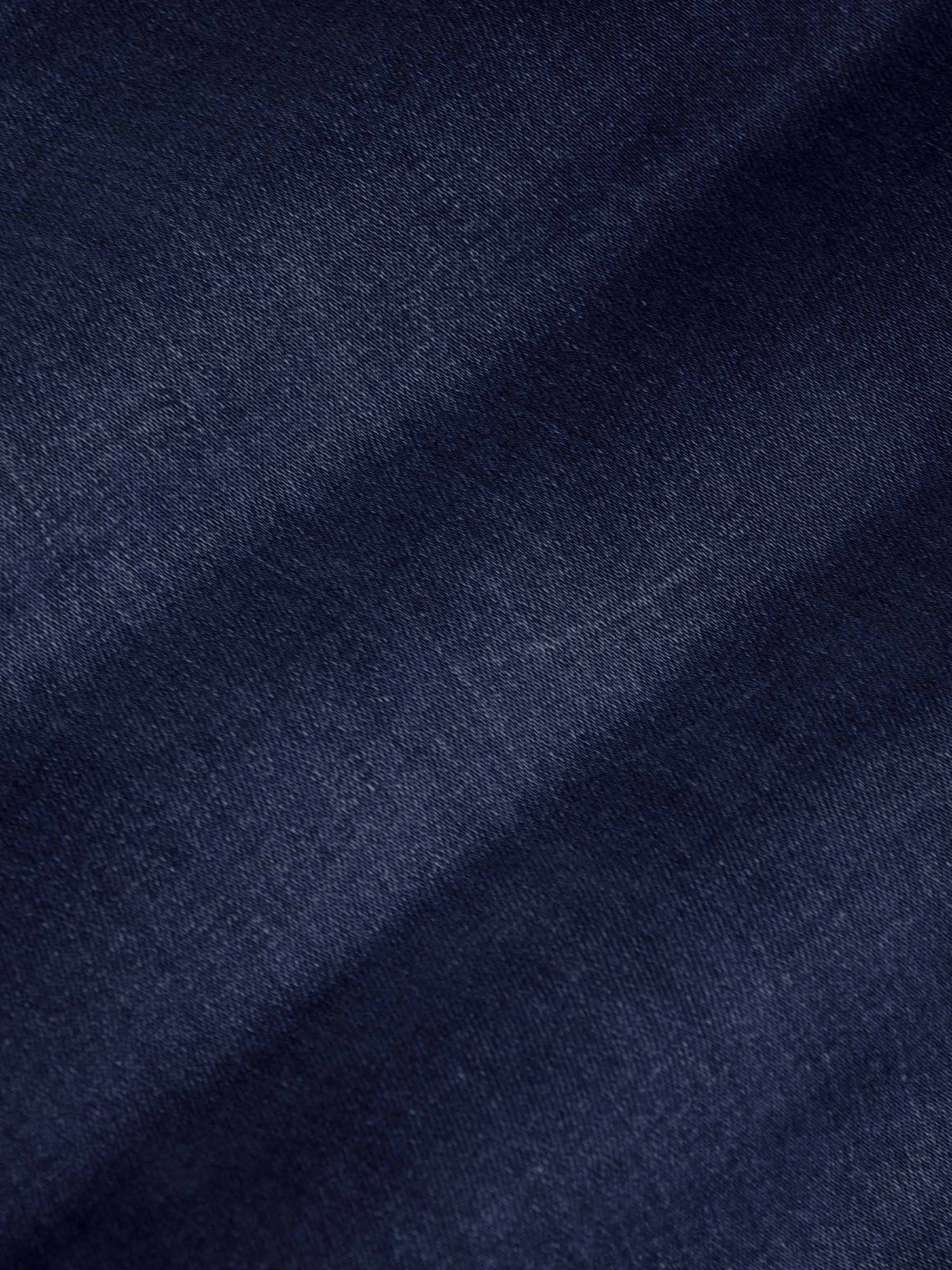 Close-up of dark navy denim fabric texture showing smooth weave and slight fade – Wam Denim.