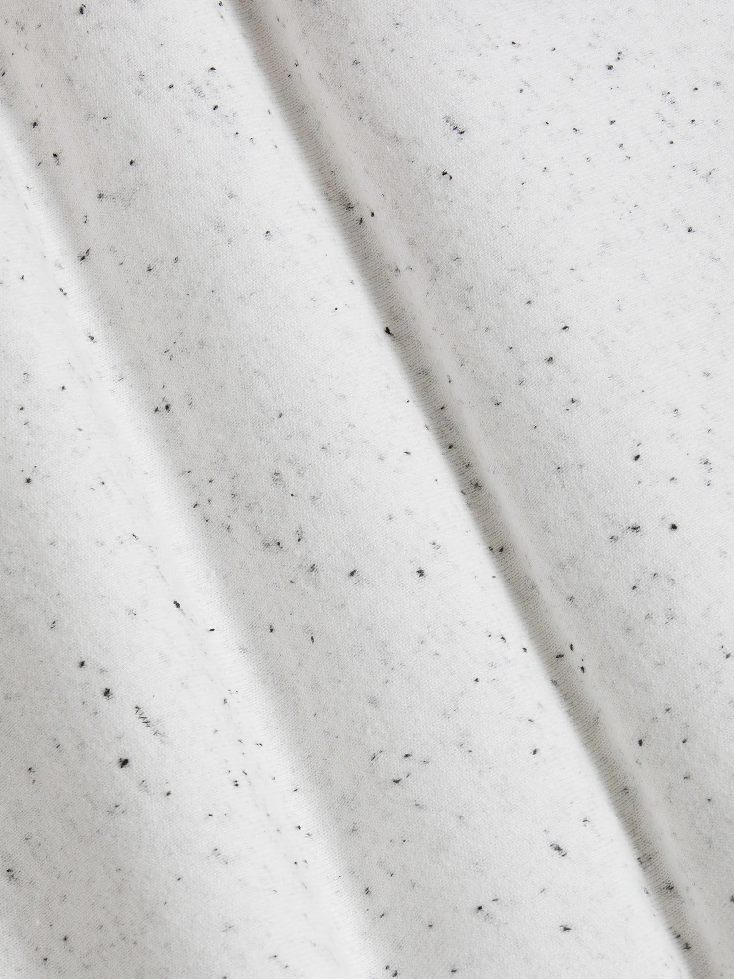 Close-up of a textured white fabric with black specks