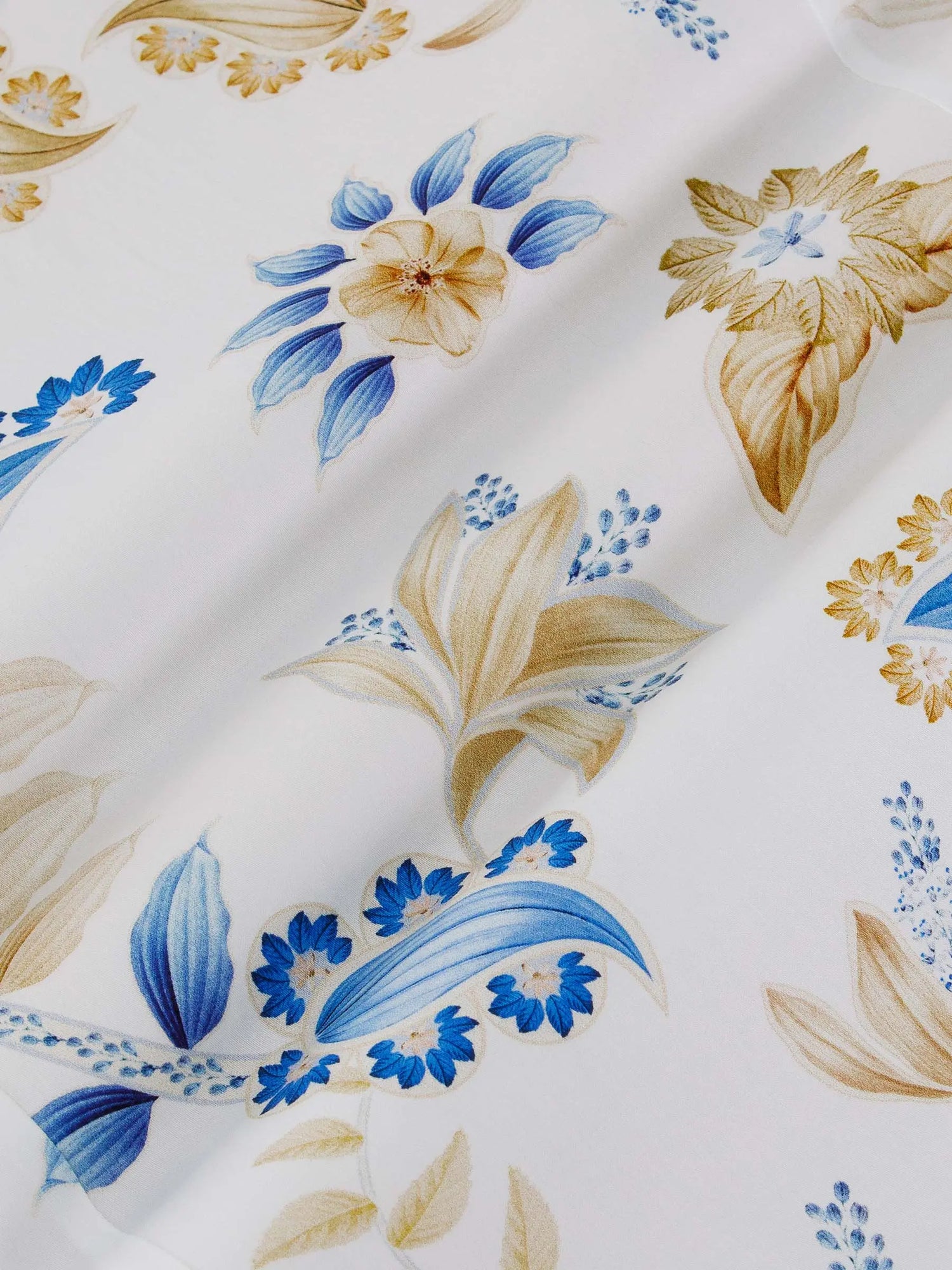 Close-up of white floral fabric with blue and beige flower pattern details – Wam Denim.