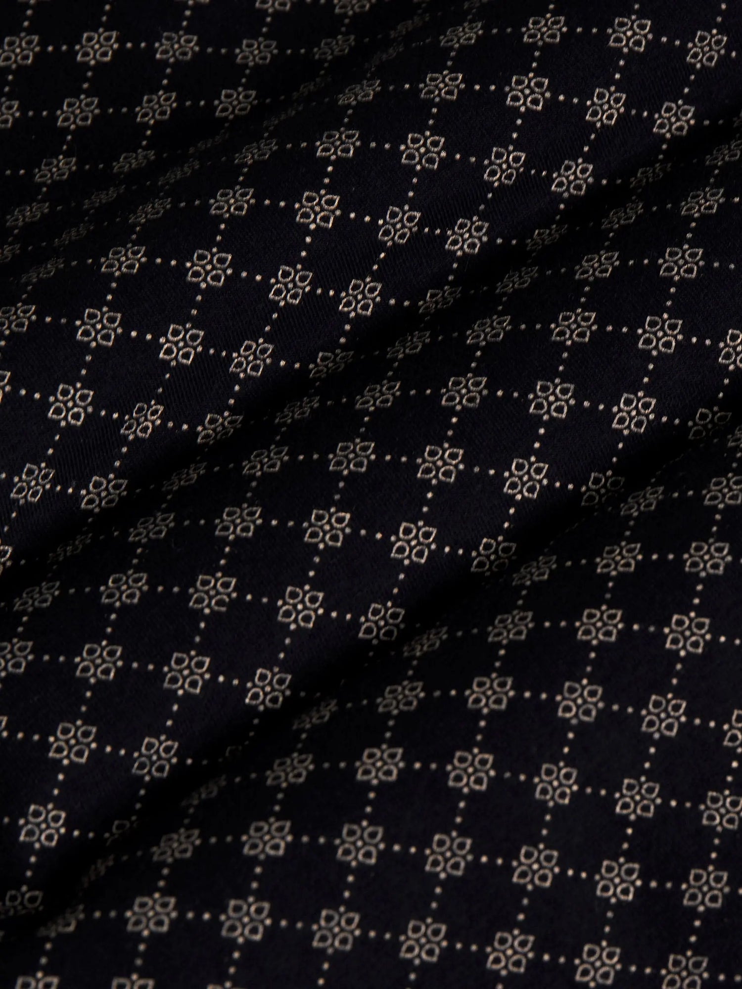Close-up of black fabric with beige geometric pattern showing soft textured weave – Wam Denim.
