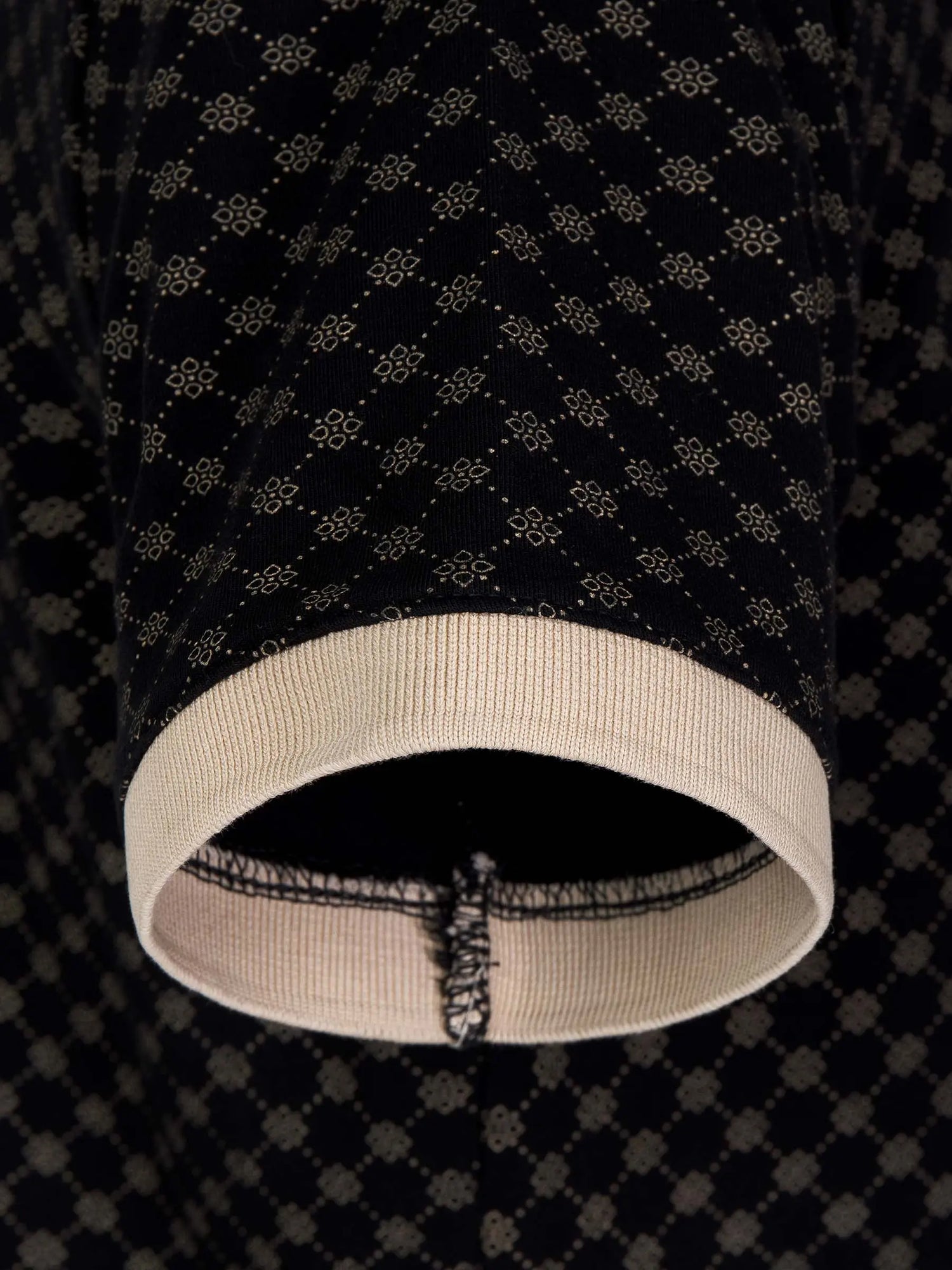 Close-up of polo sleeve showing beige ribbed cuff and geometric black fabric – Wam Denim.
