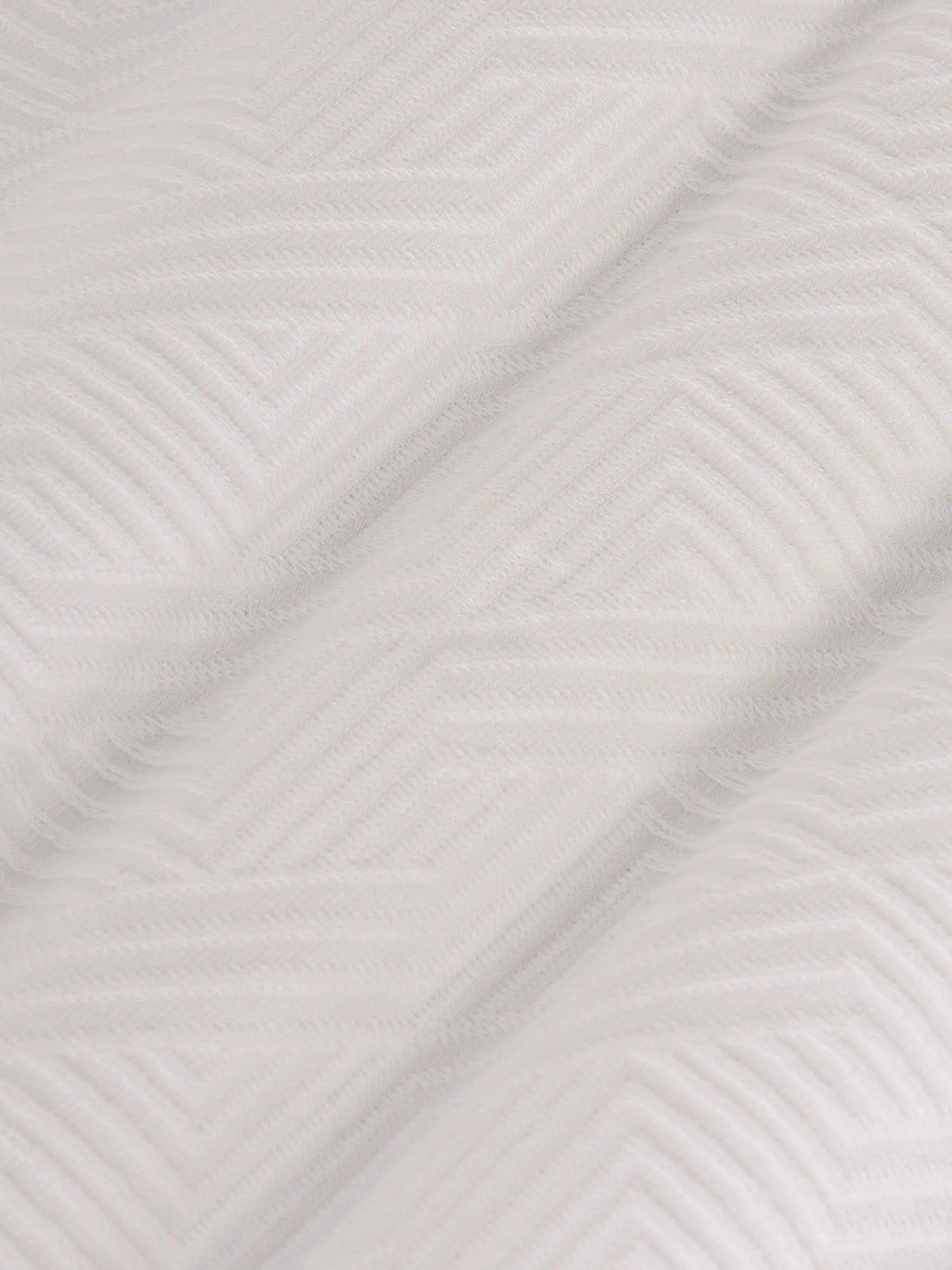 Close-up of the textured white fabric with a geometric pattern – Wam Denim.