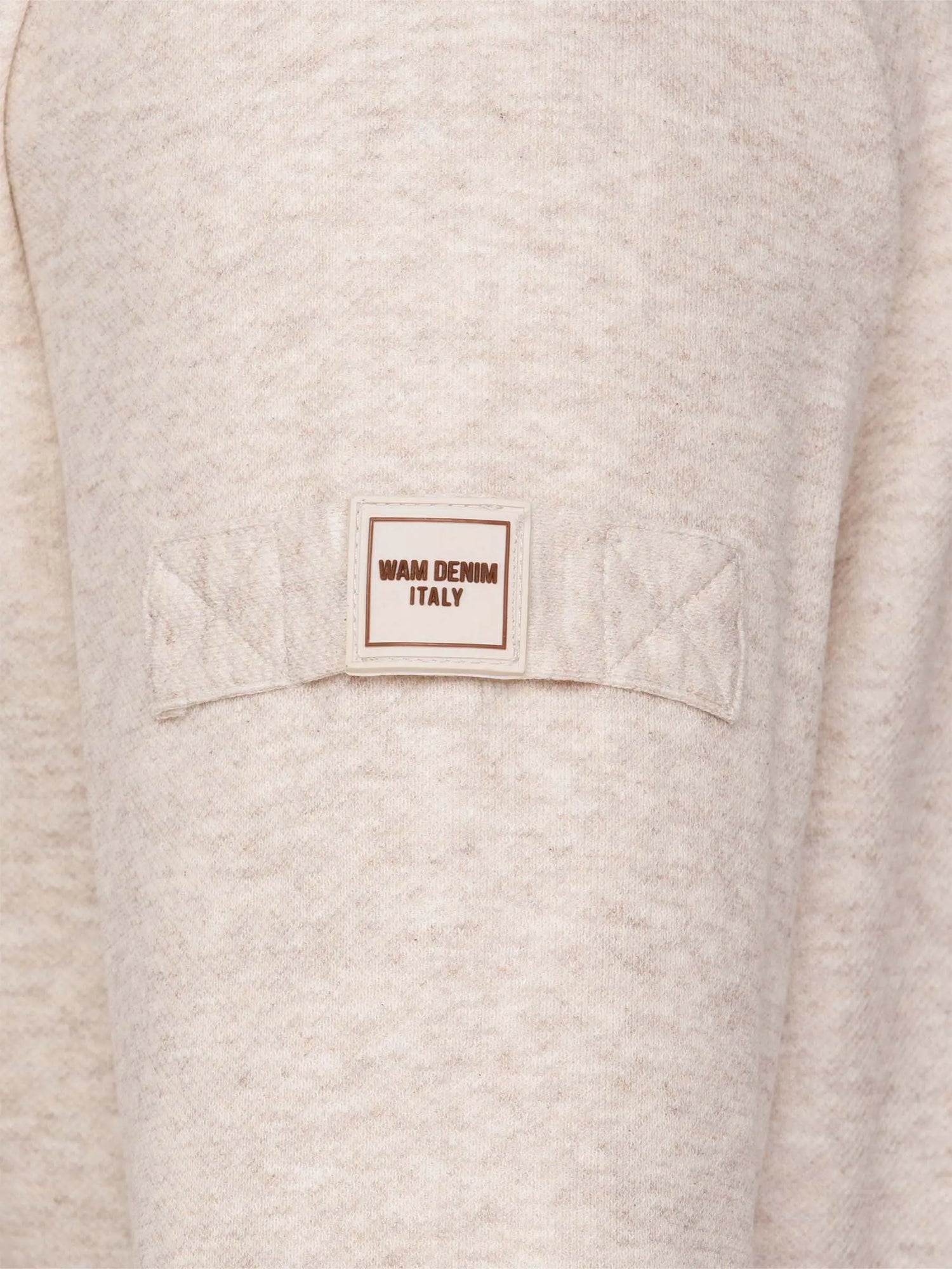 Close-up of a beige garment with a 'WAM Denim Italy' label on a pocket.