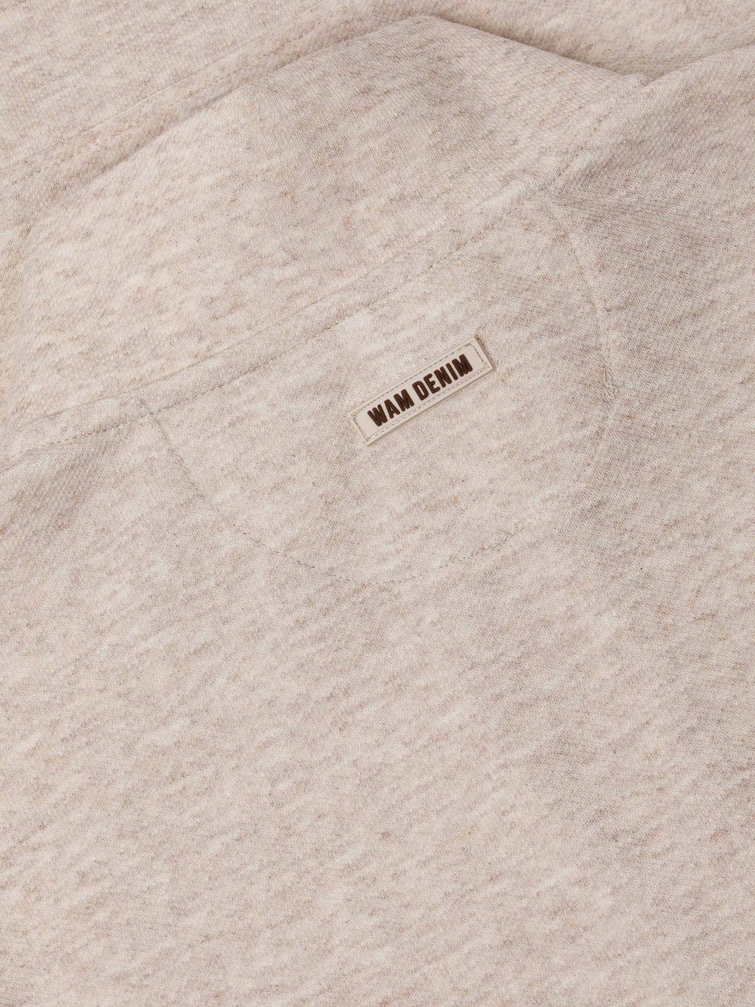 Close-up of beige fabric with a 'Wam Denim' label.