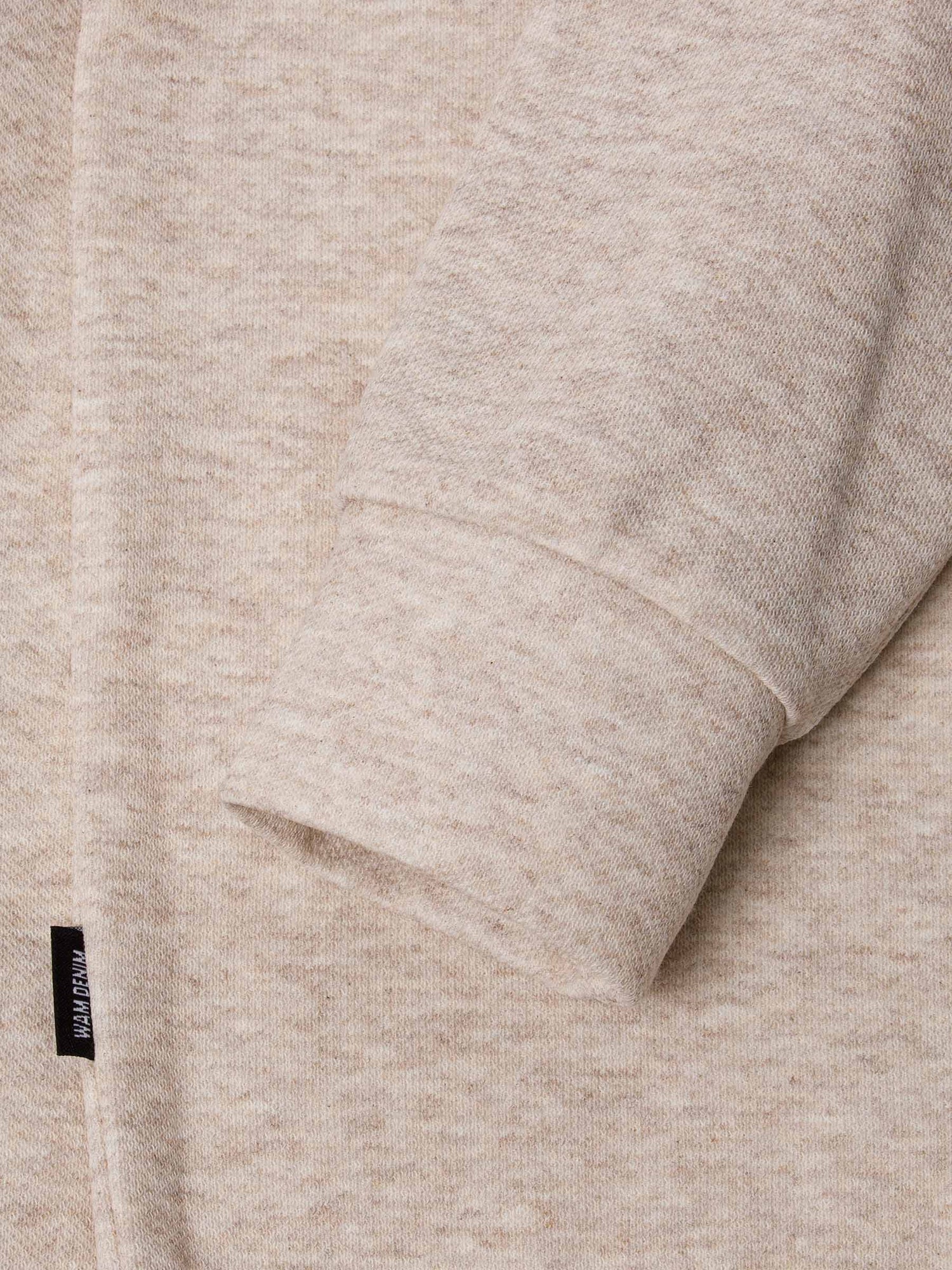Close-up of a beige fleece fabric with a brand label.
