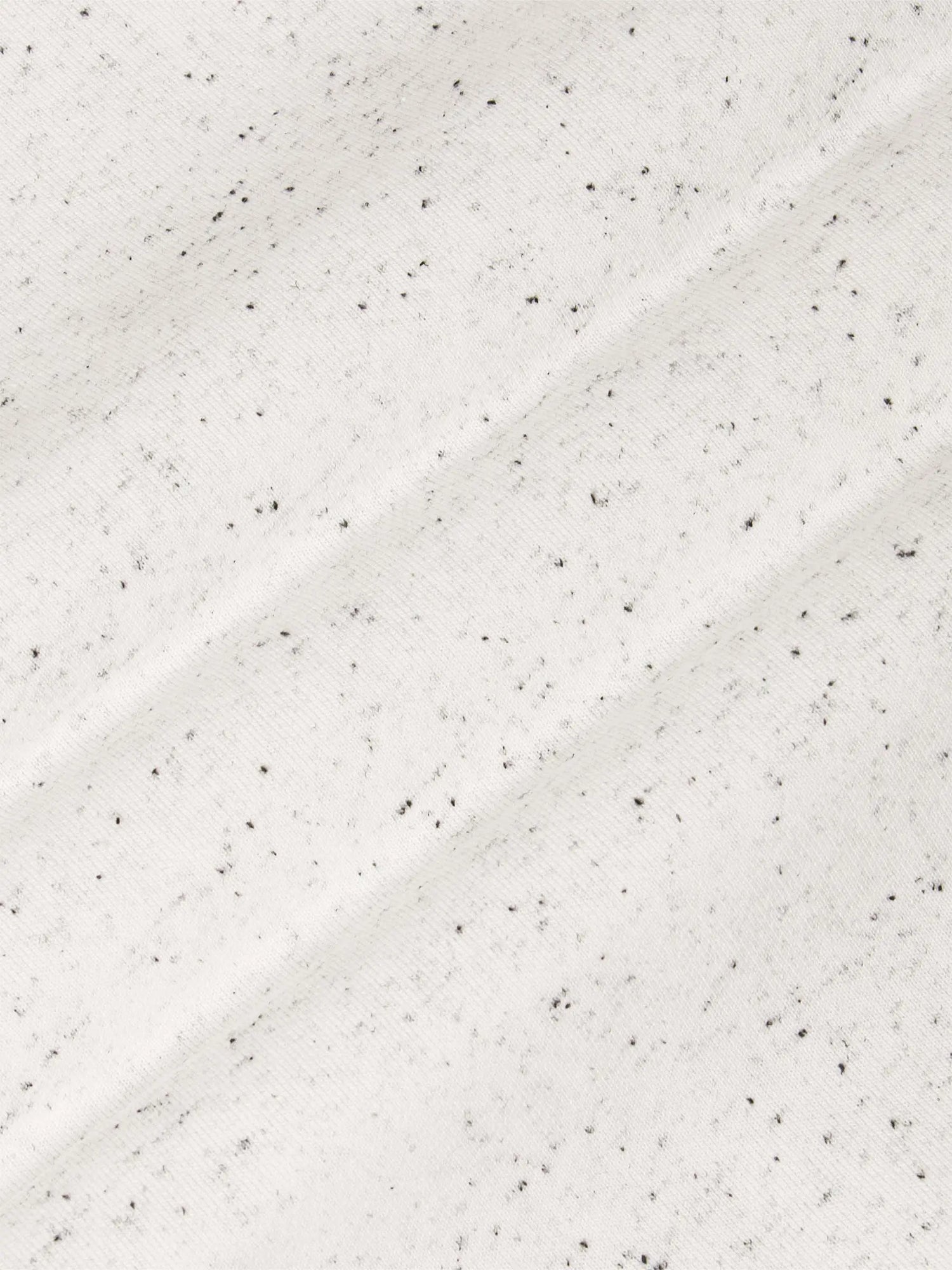 Close-up of a textured white surface with small black specks