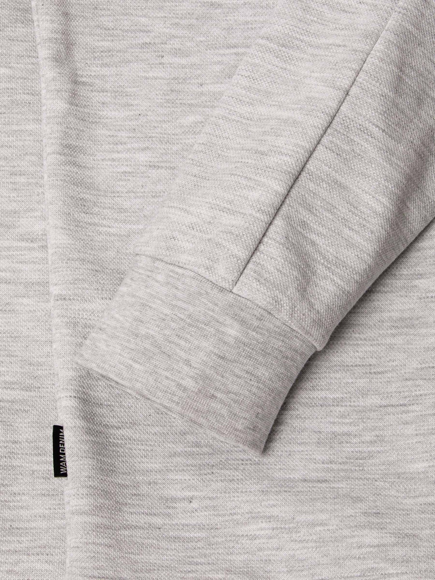 Close-up of light grey sweatshirt sleeve with ribbed cuff and woven label – Wam Denim.
