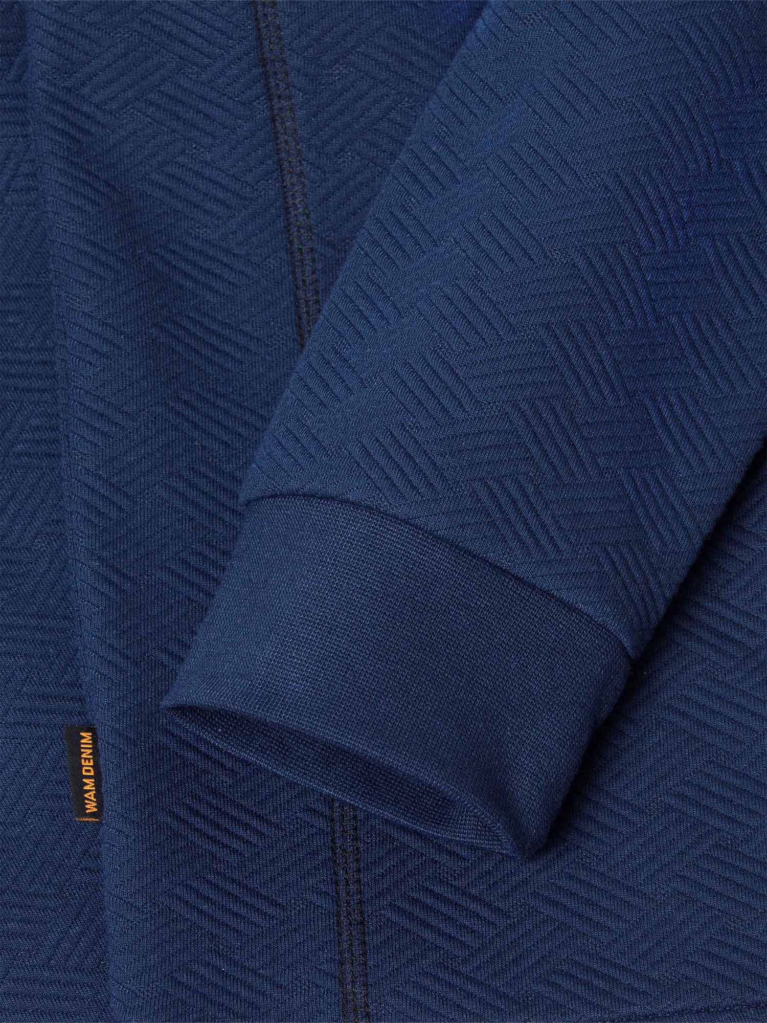 Close-up of navy Moorland Sweater sleeve with logo. – Wam Denim.