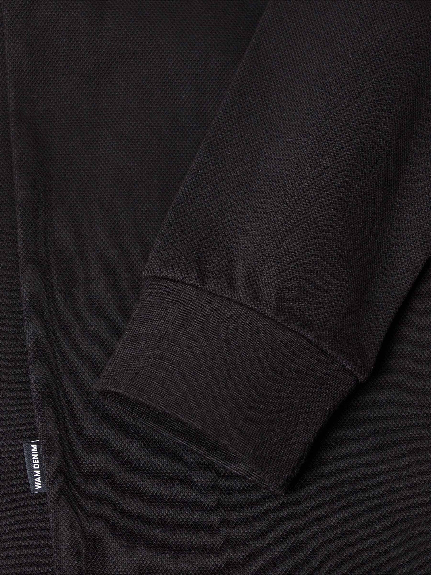 Close-up of black sweater sleeve with ribbed cuff and woven texture detail – Wam Denim.
