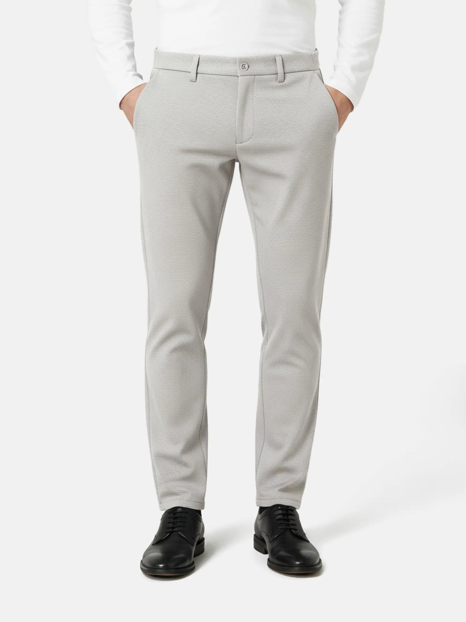 Front view of light grey slim-fit men’s pantalon styled with black dress shoes.