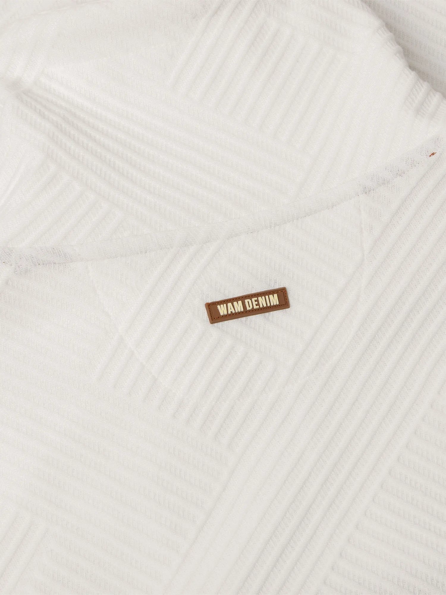 Close-up of white textured sweatshirt fabric with stitched Wam Denim logo patch – Wam Denim.