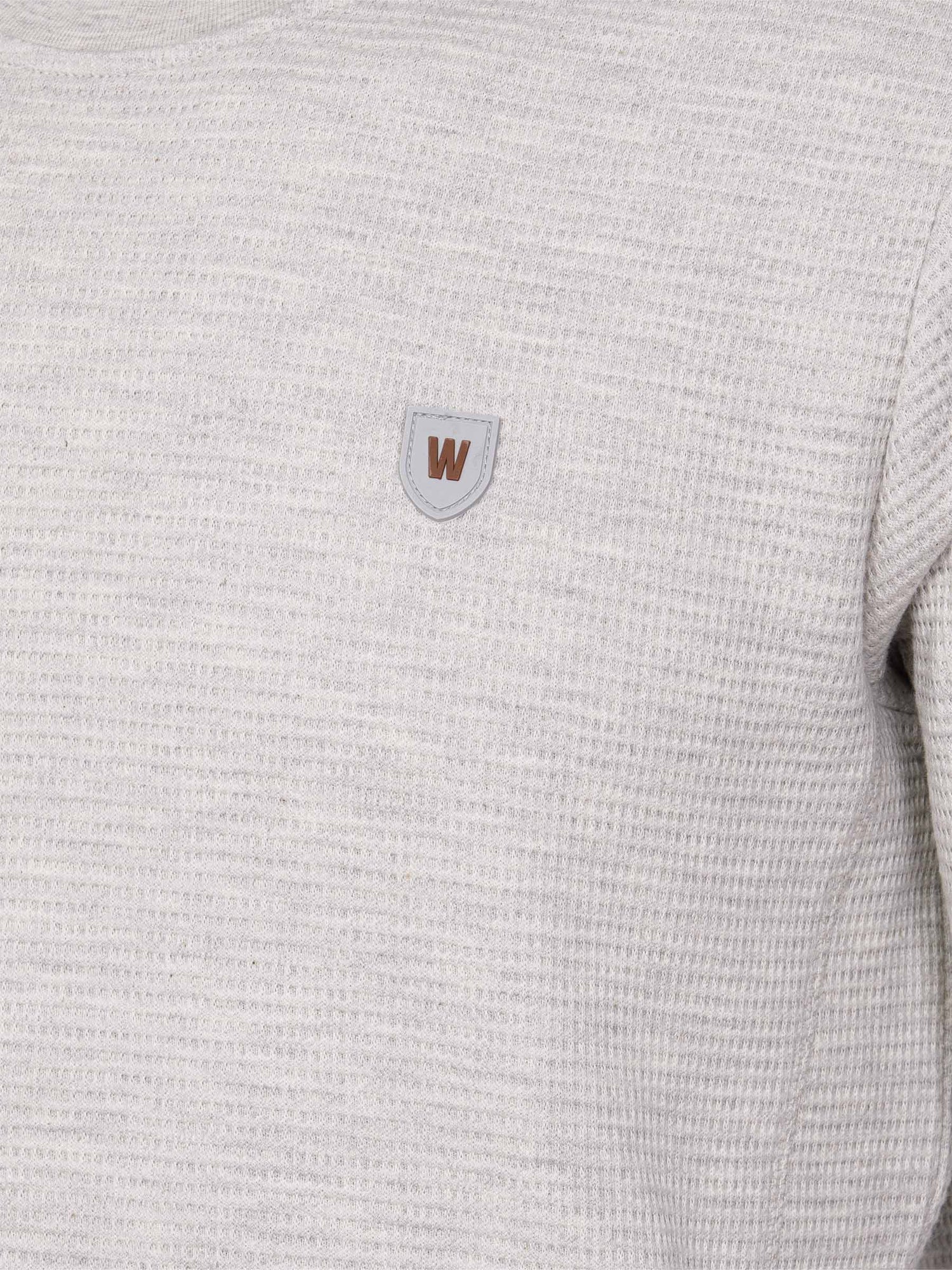 Close-up of light grey textured sweatshirt with brown and grey chest logo patch – Wam Denim.