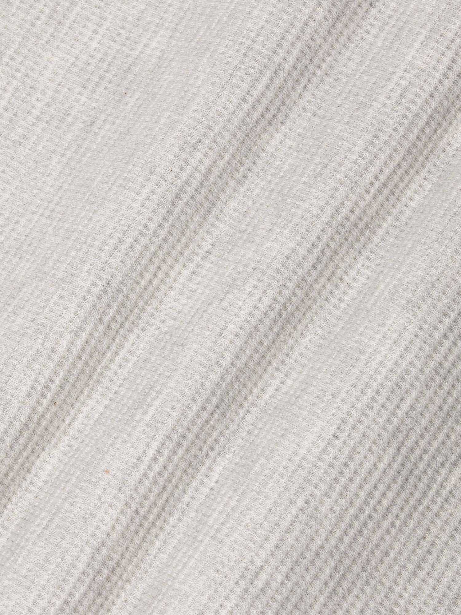 Close-up of soft light grey waffle-textured fabric showing fine knit details – Wam Denim.