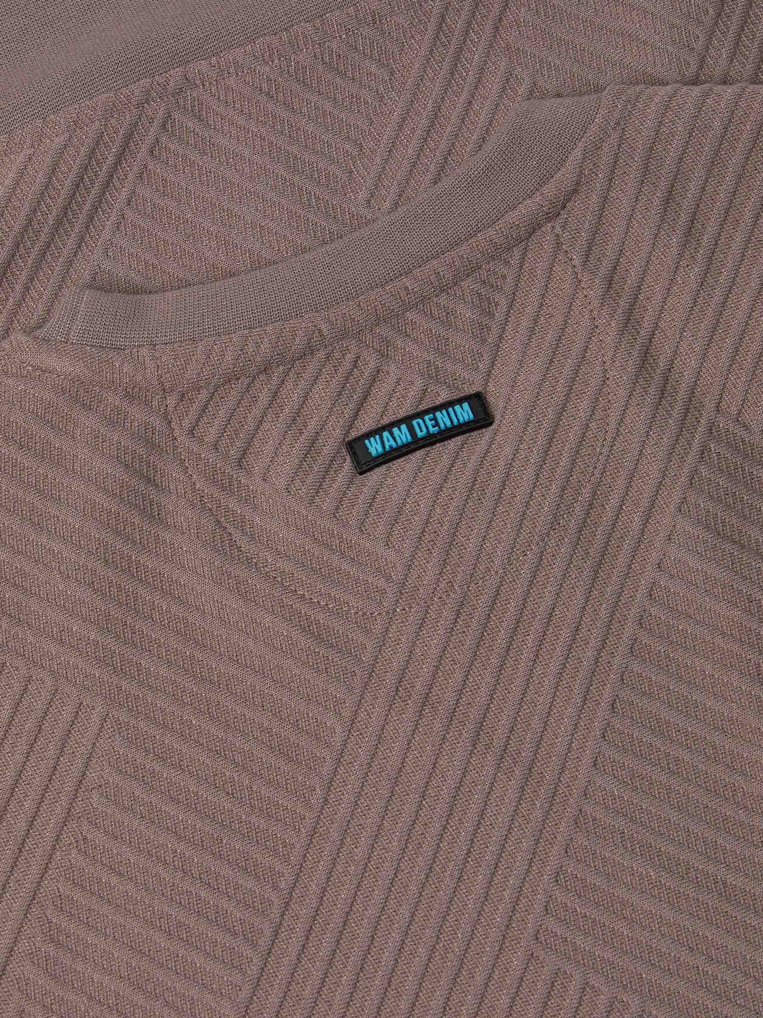 Close-up of the Wam Denim label on the textured sweater – Wam Denim.