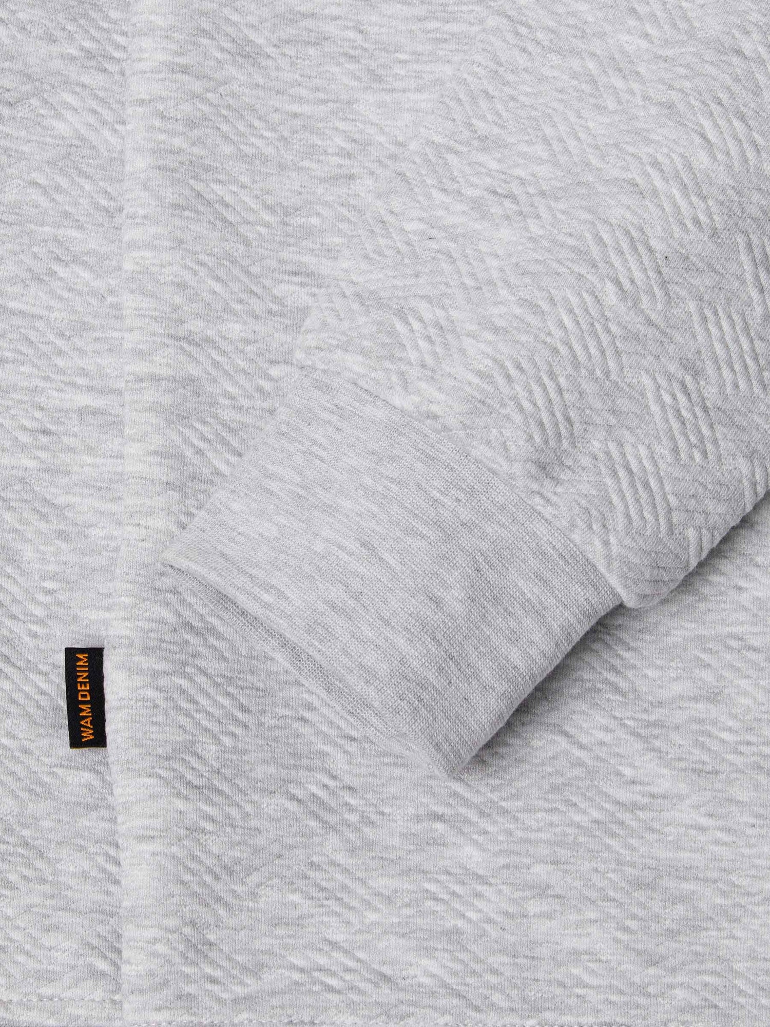 Close-up of light grey sweatshirt cuff and hem with woven Wam Denim label – Wam Denim.