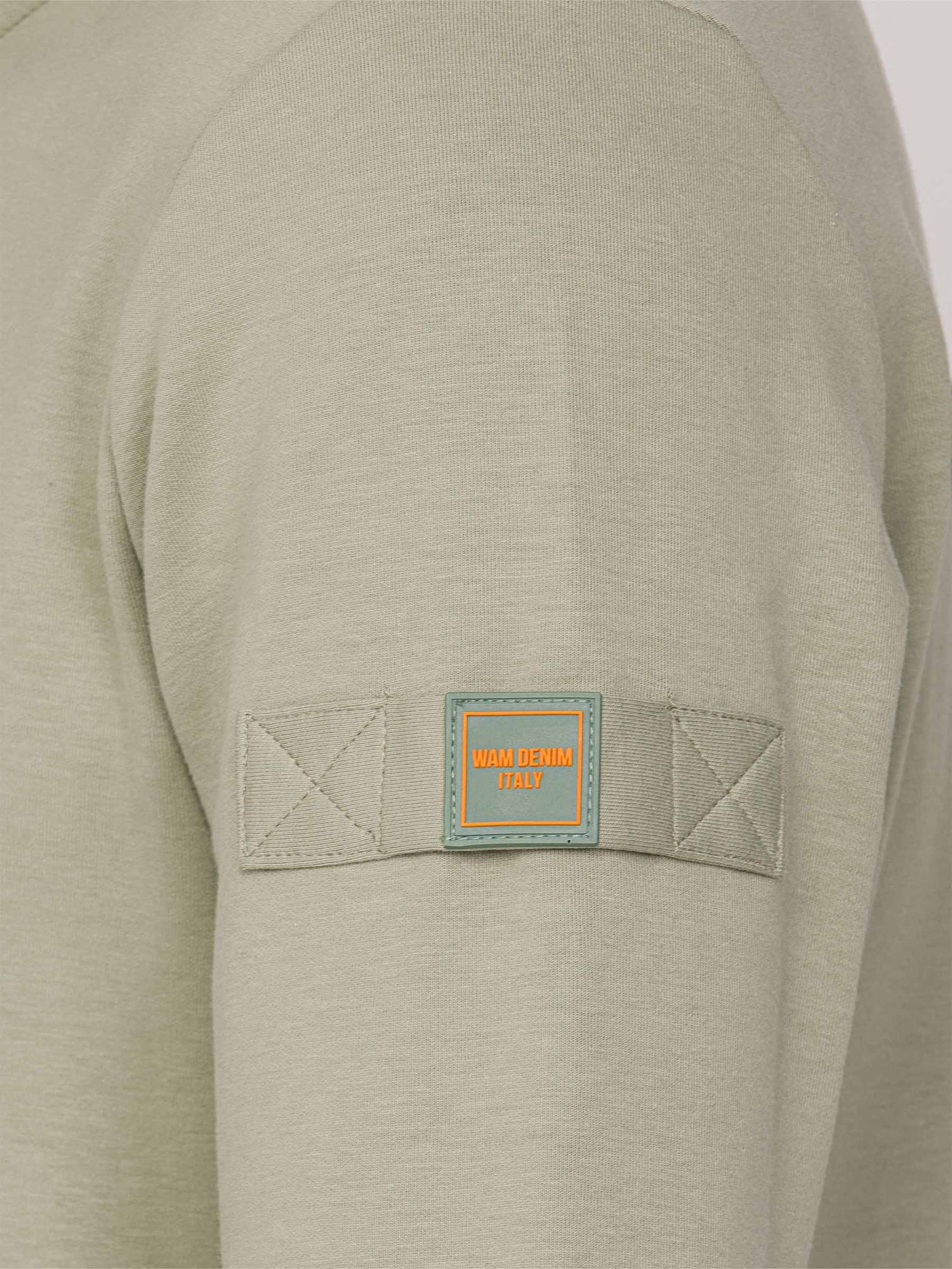 Close-up of a Light Green Sweater with a patch on the sleeve.