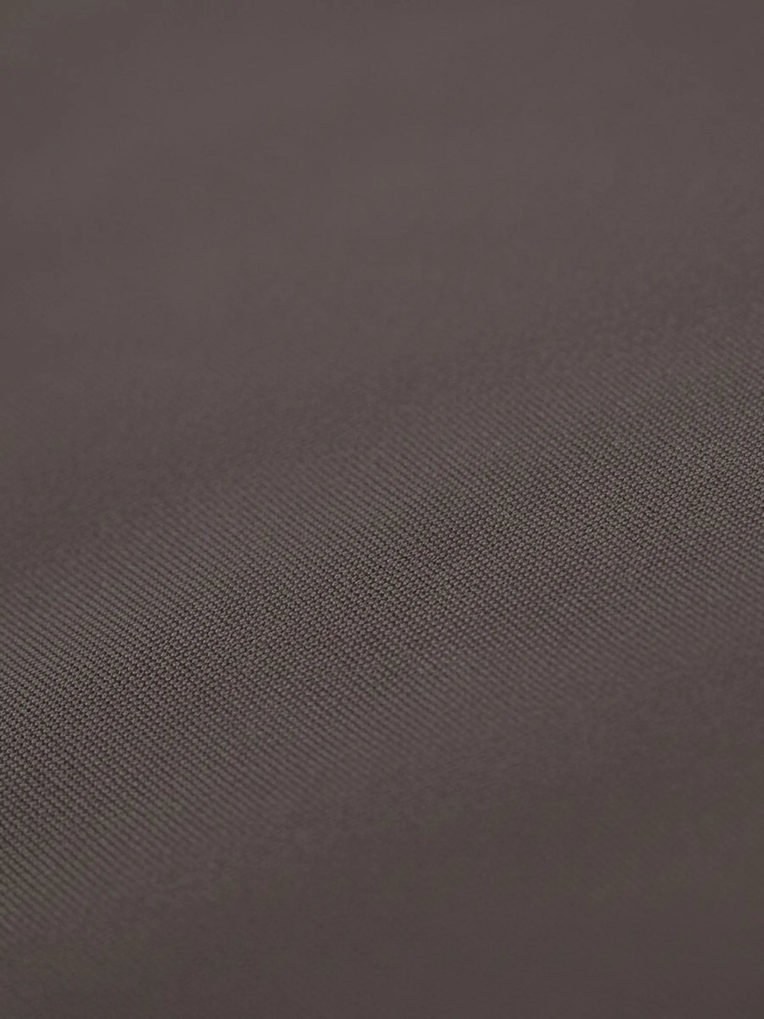 Close-up of light brown shirt fabric with smooth texture and fine weave.