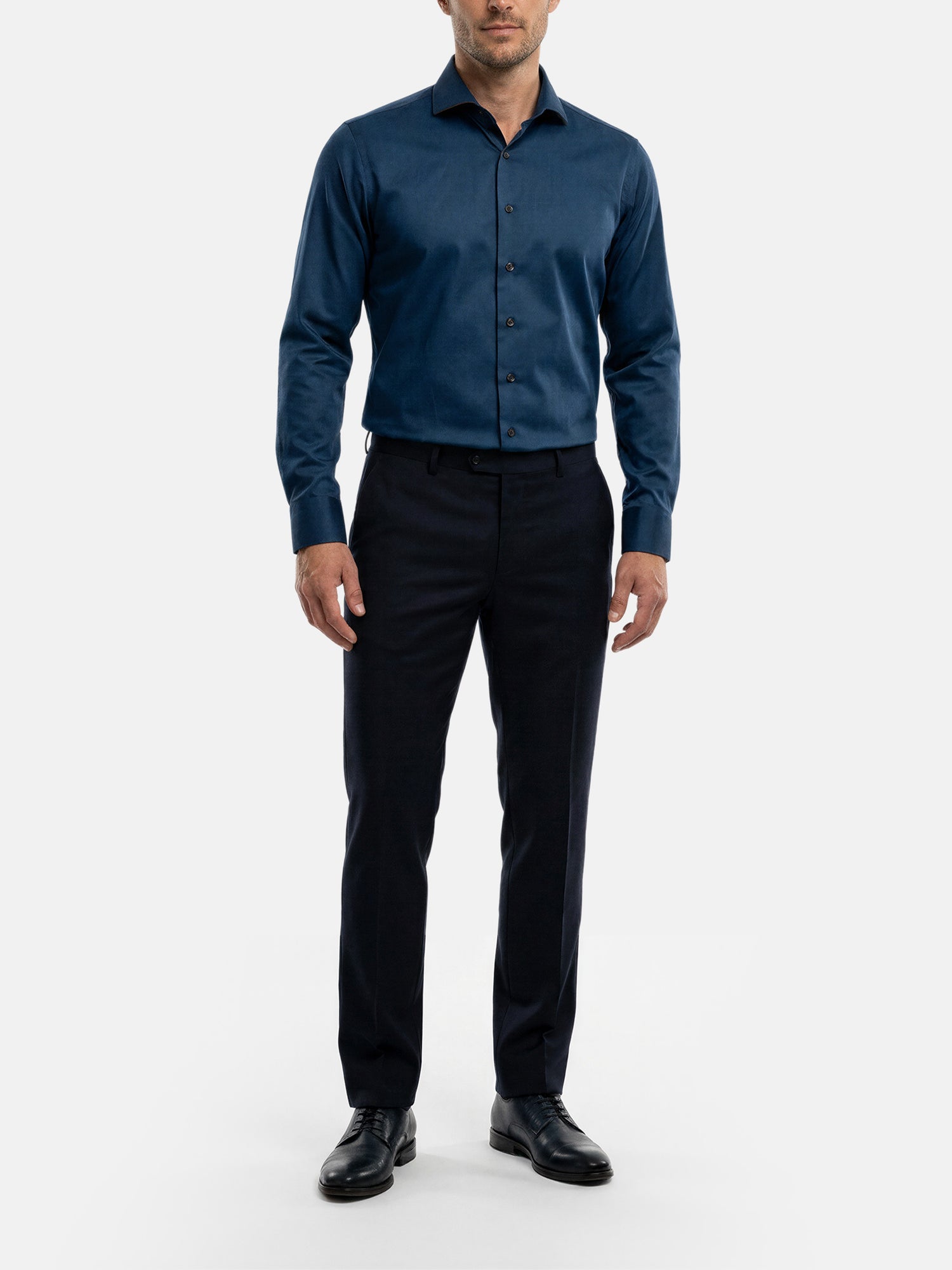 Model wearing petrol blue men’s dress shirt styled with black trousers and formal shoes.