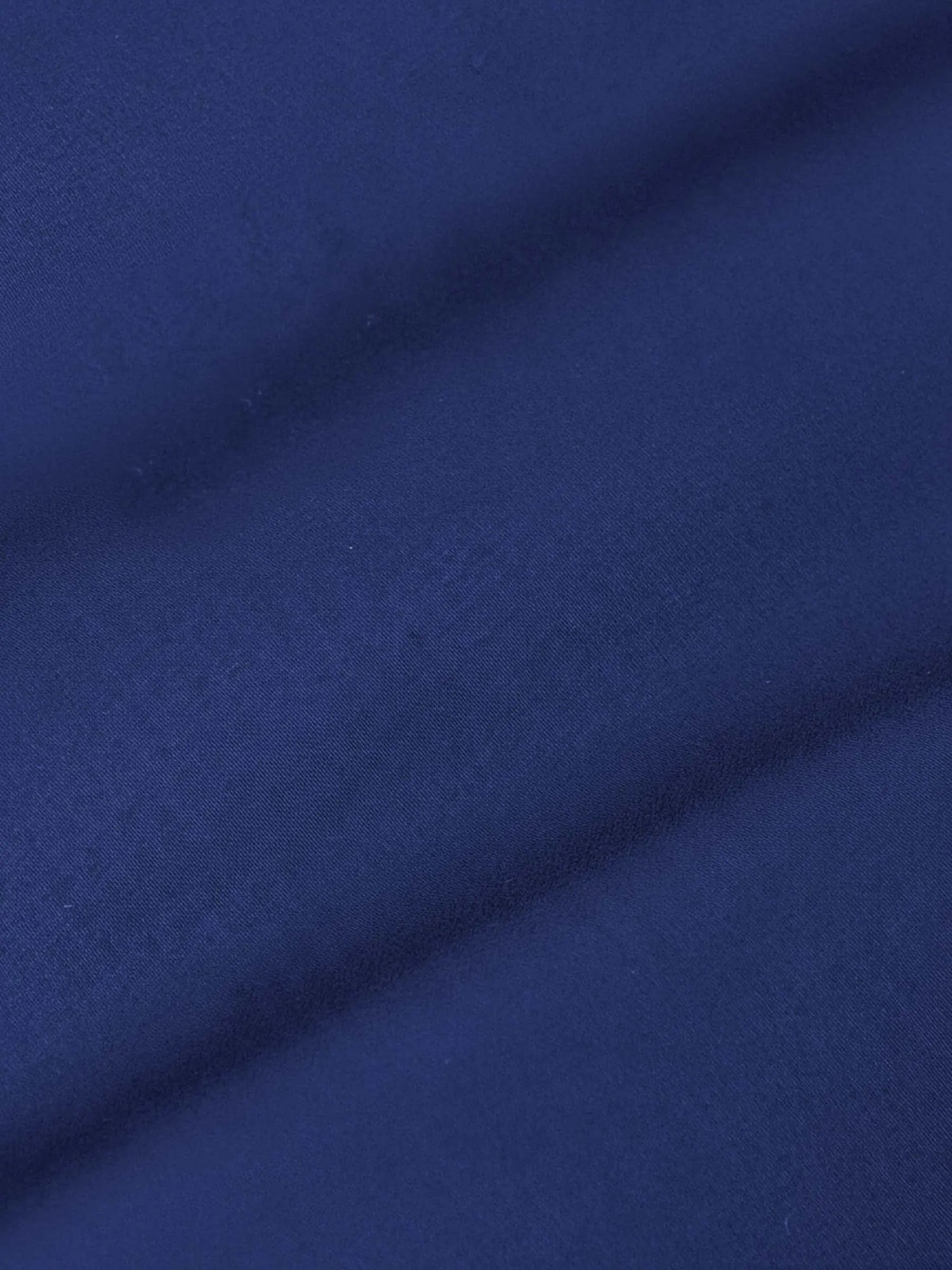 Close-up of royal blue shirt fabric showing smooth texture and fine weave.