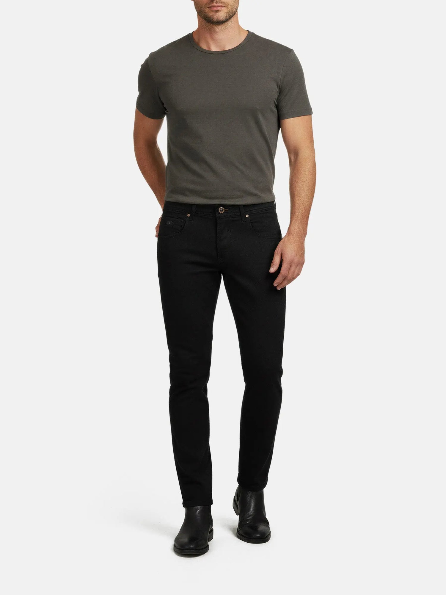 Full-body view of a man wearing black slim-fit jeans styled with a basic t-shirt.