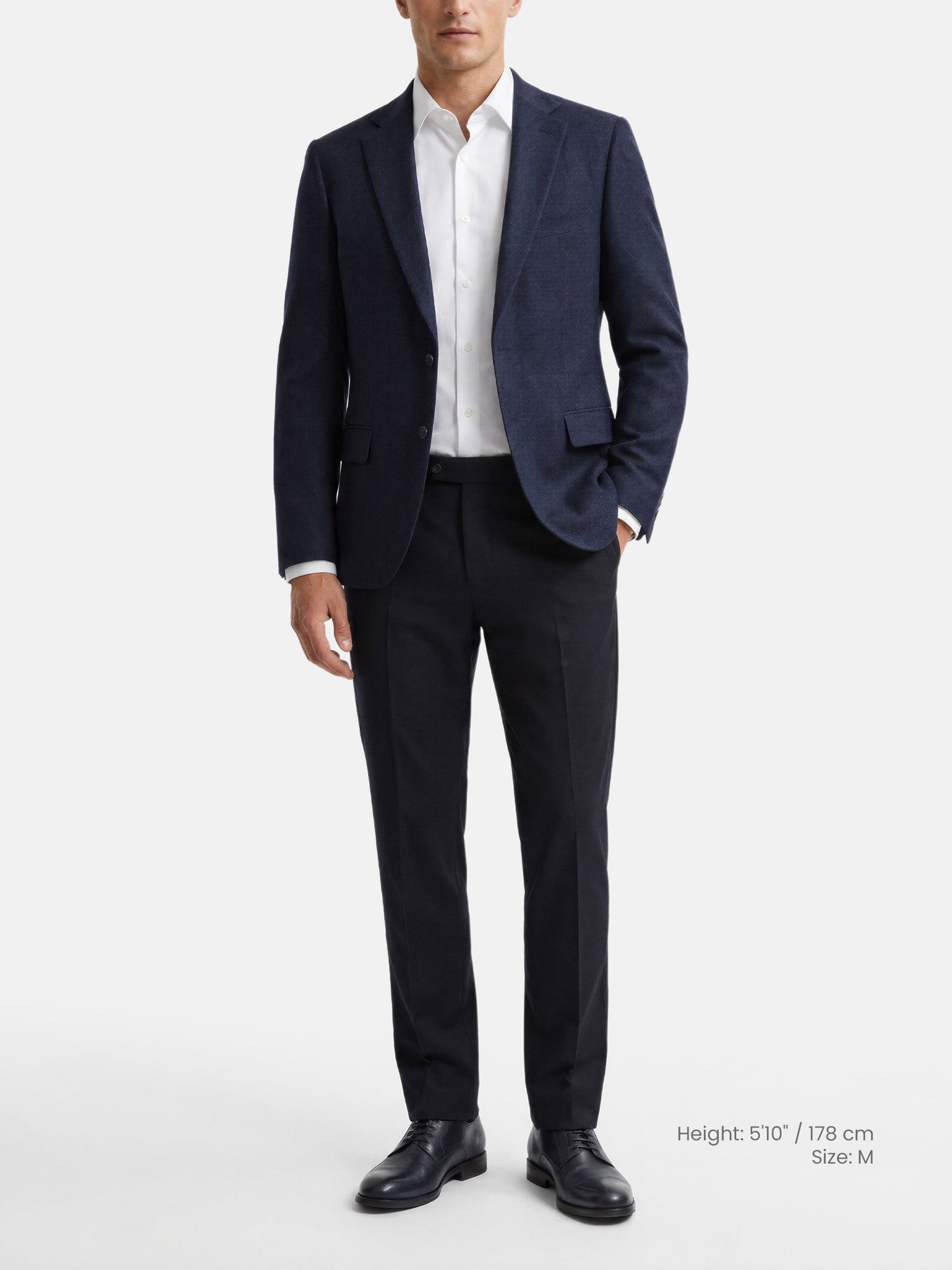 Model wearing slim fit navy men’s blazer styled with white shirt and trousers.