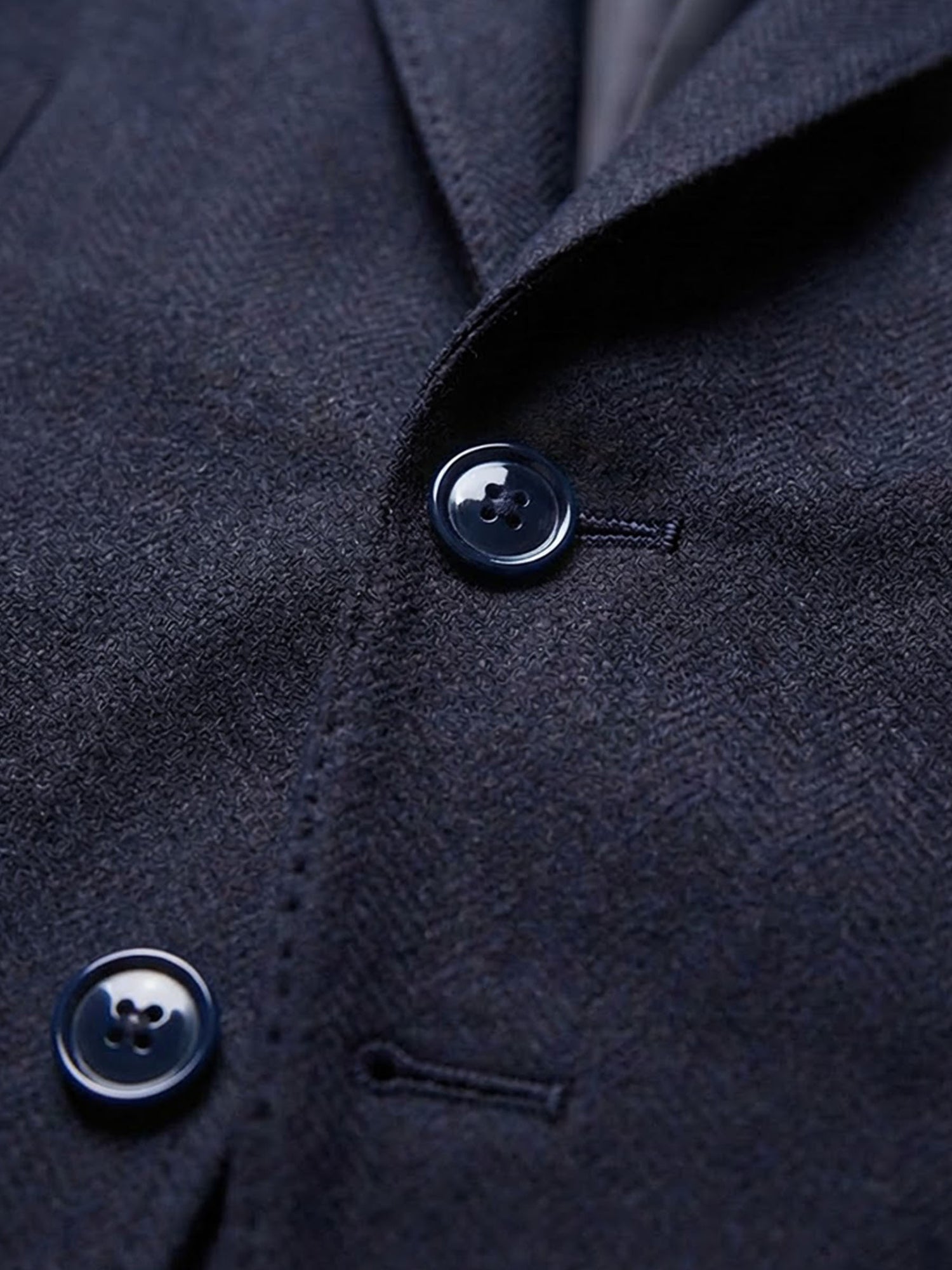 Close-up of navy blazer button and textured fabric detail.