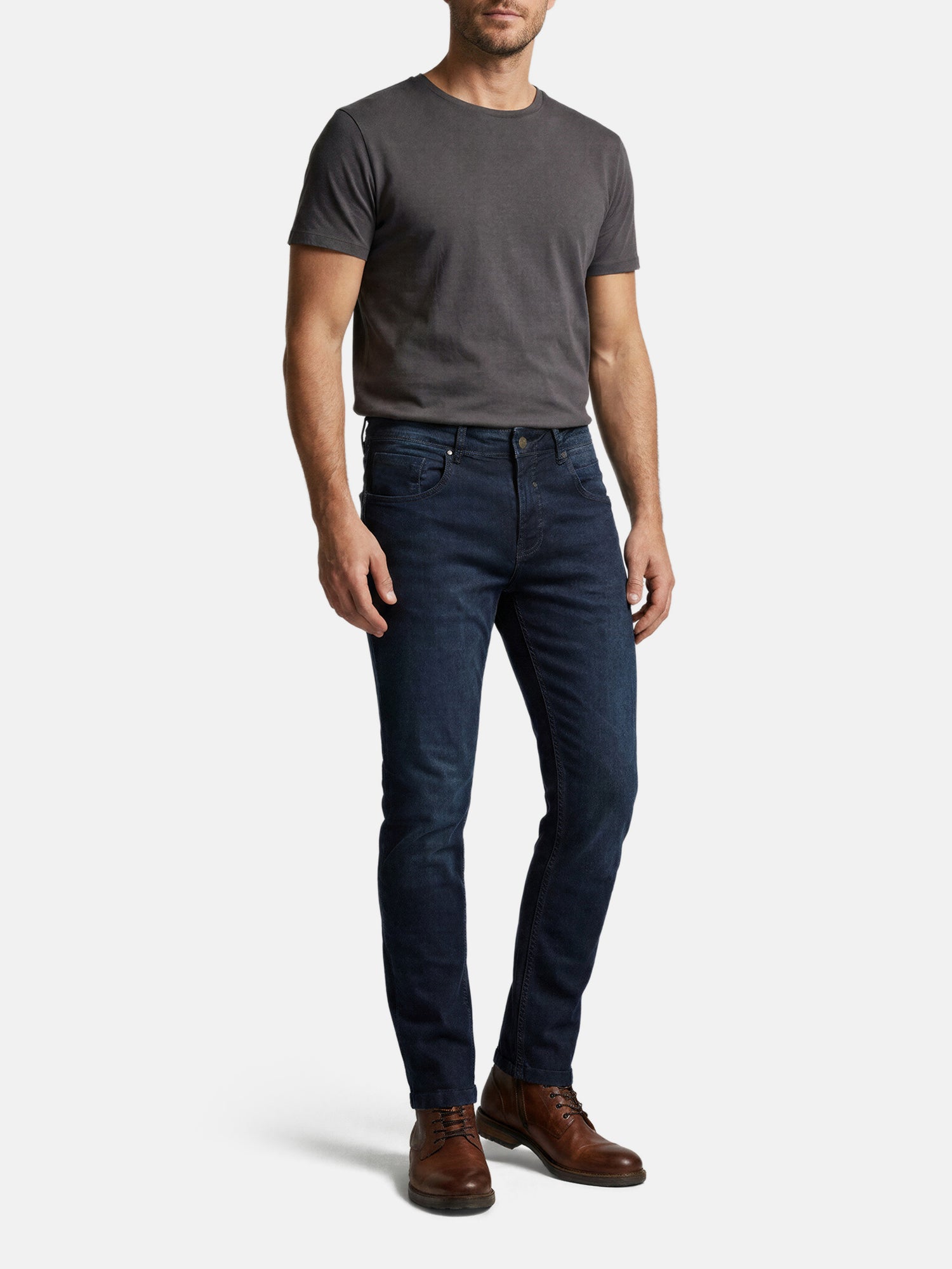 Model wearing navy men’s slim fit jeans styled casually with t-shirt and boots.