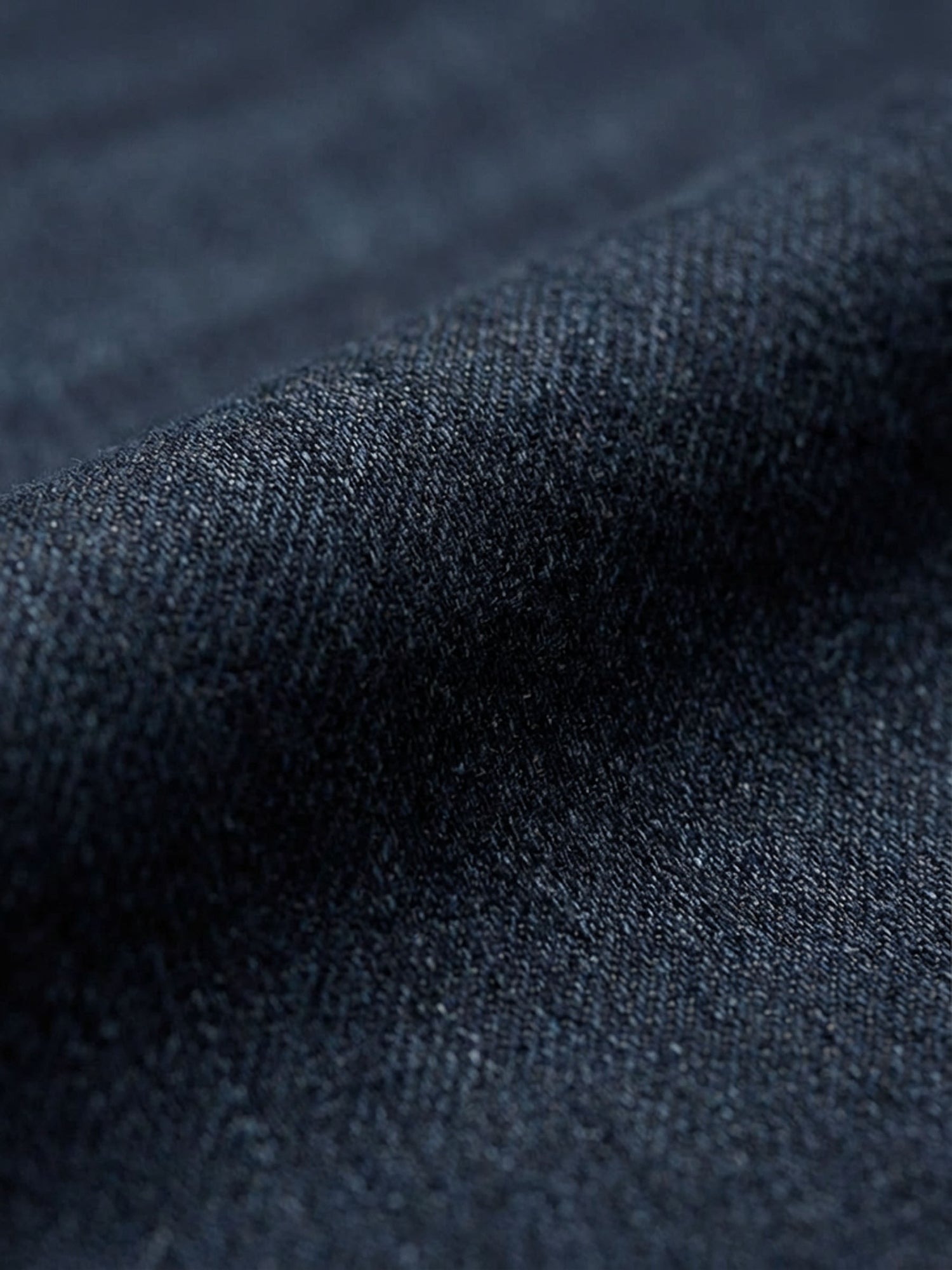Close-up of navy denim fabric showing smooth weave and premium jean texture.