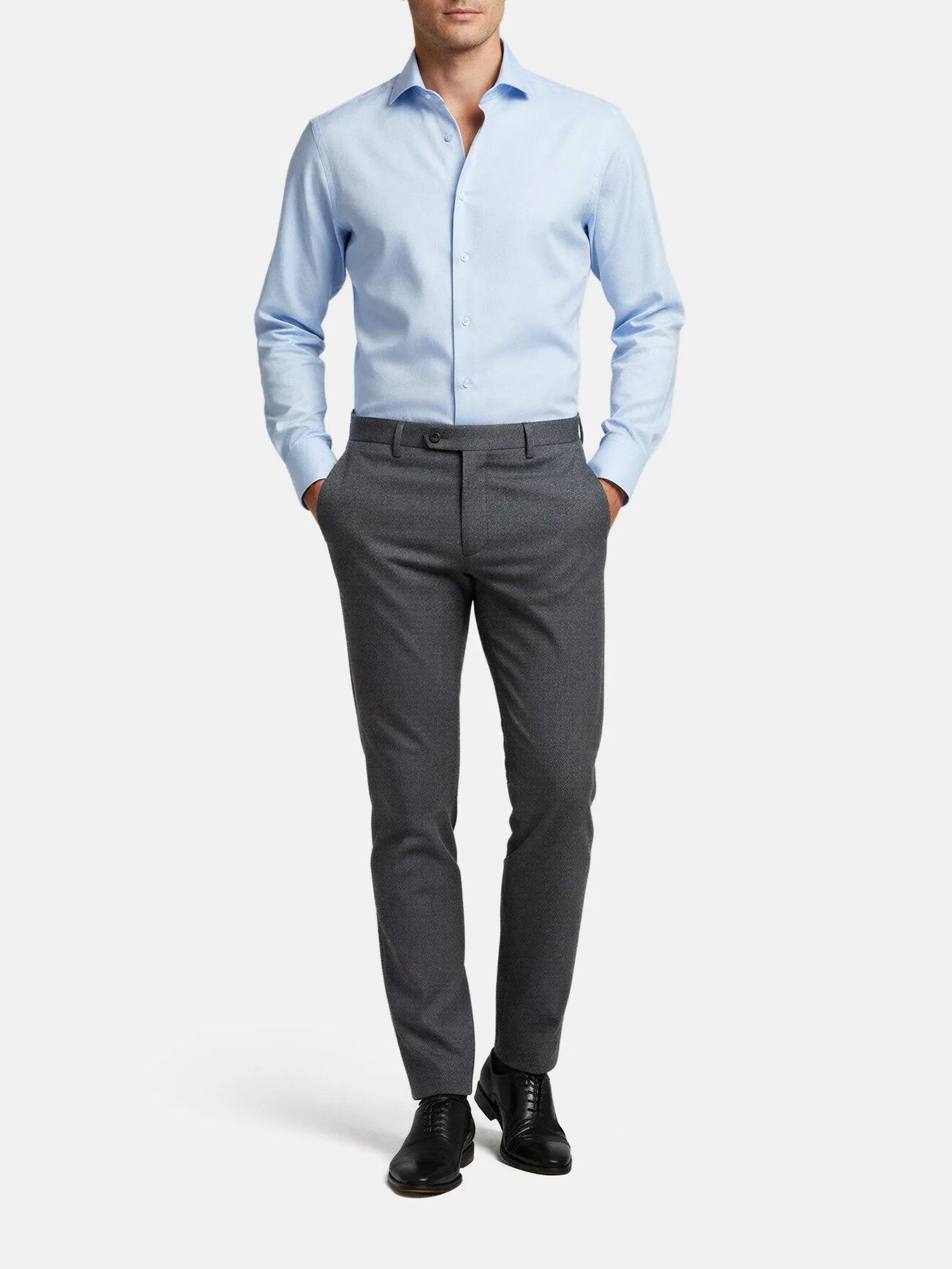 Model wearing blue dress shirt with grey trousers, smart formal outfit.