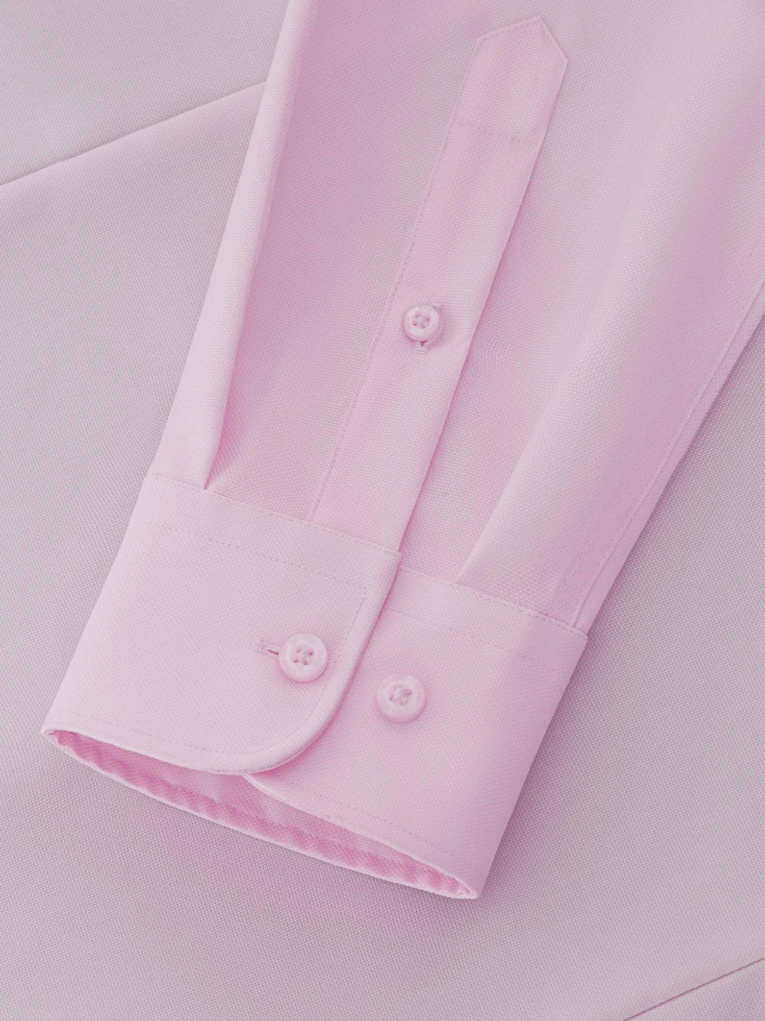 Close-up of pink dress shirt cuff and textured fabric detail.