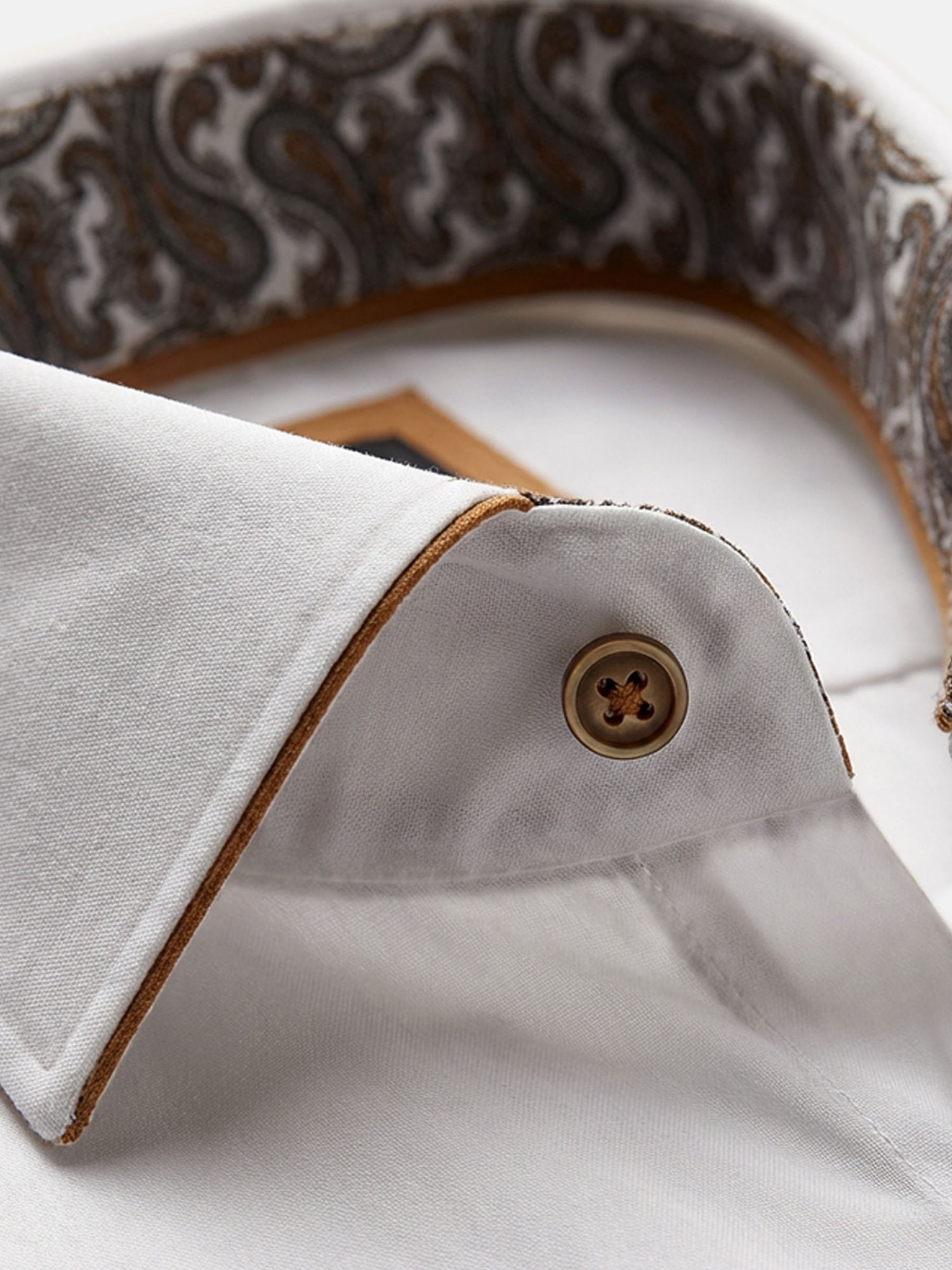 Close-up of white dress shirt collar with contrast trim and premium button detail.