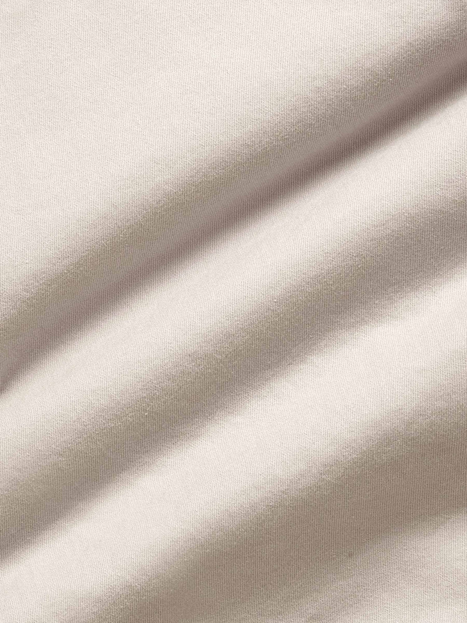 Light beige chino fabric close-up showing smooth cotton texture and premium weave.