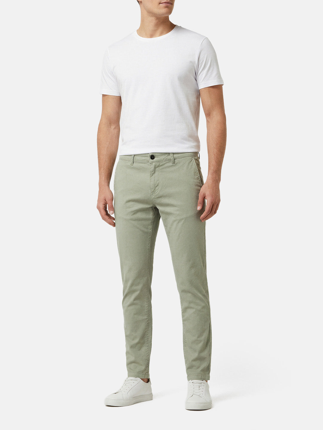 Model wearing light green slim-fit men’s chino pants styled with white t-shirt.