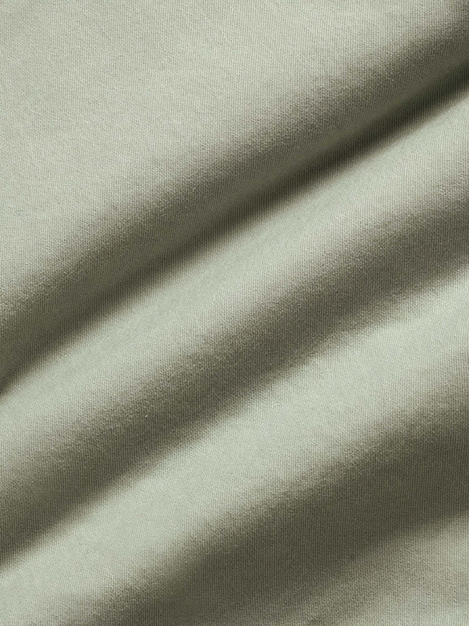 Light green chino fabric close-up showing smooth cotton texture and premium weave.