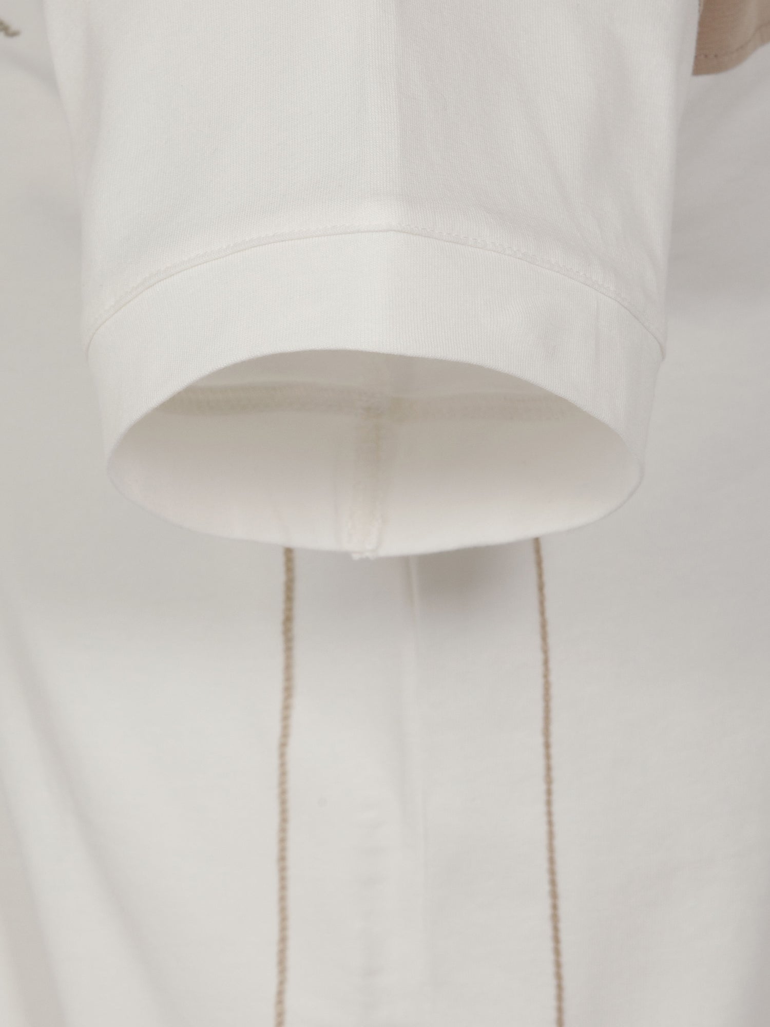 Close-up of off-white men’s T-shirt hem with clean stitching detail