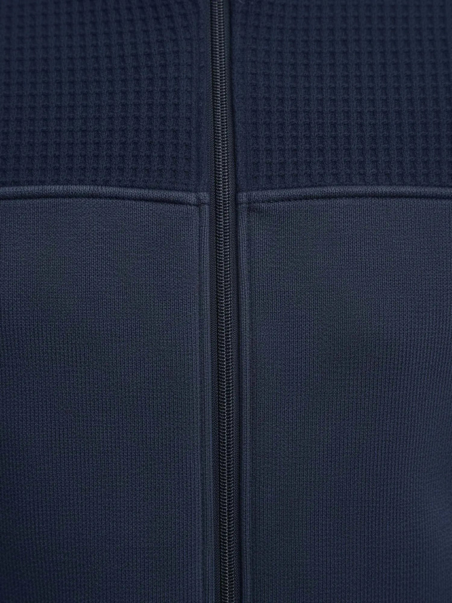 Close-up of Light Indigo jacket fabric showing textured upper panel and central zipper.