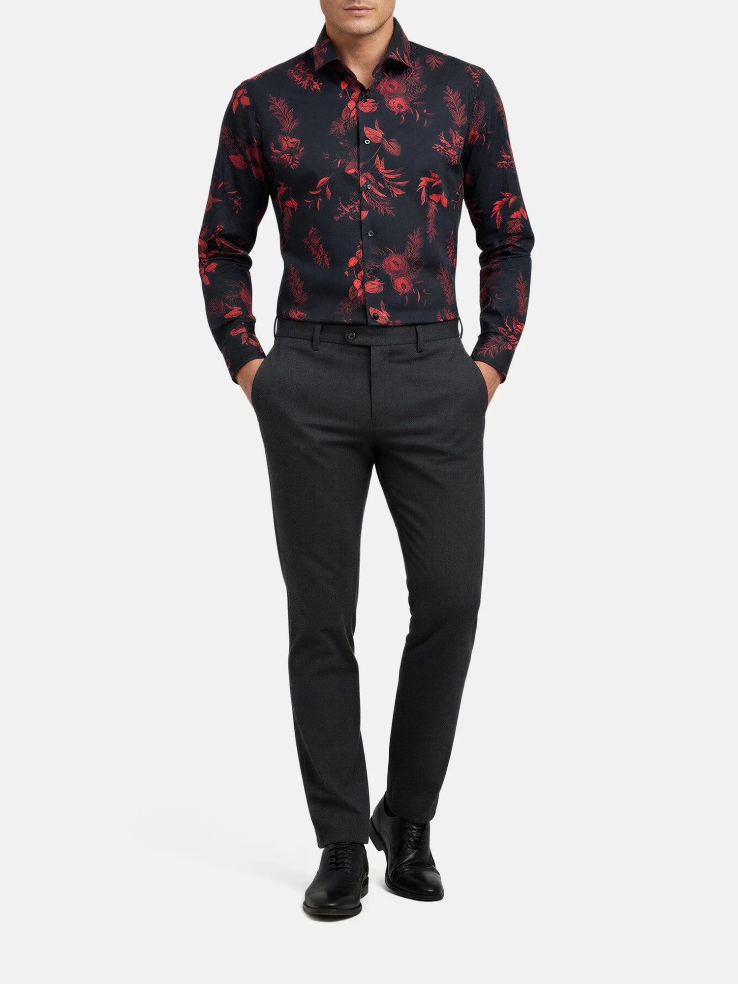 Man wearing a black shirt with red floral print, paired with dark trousers and dress shoes.