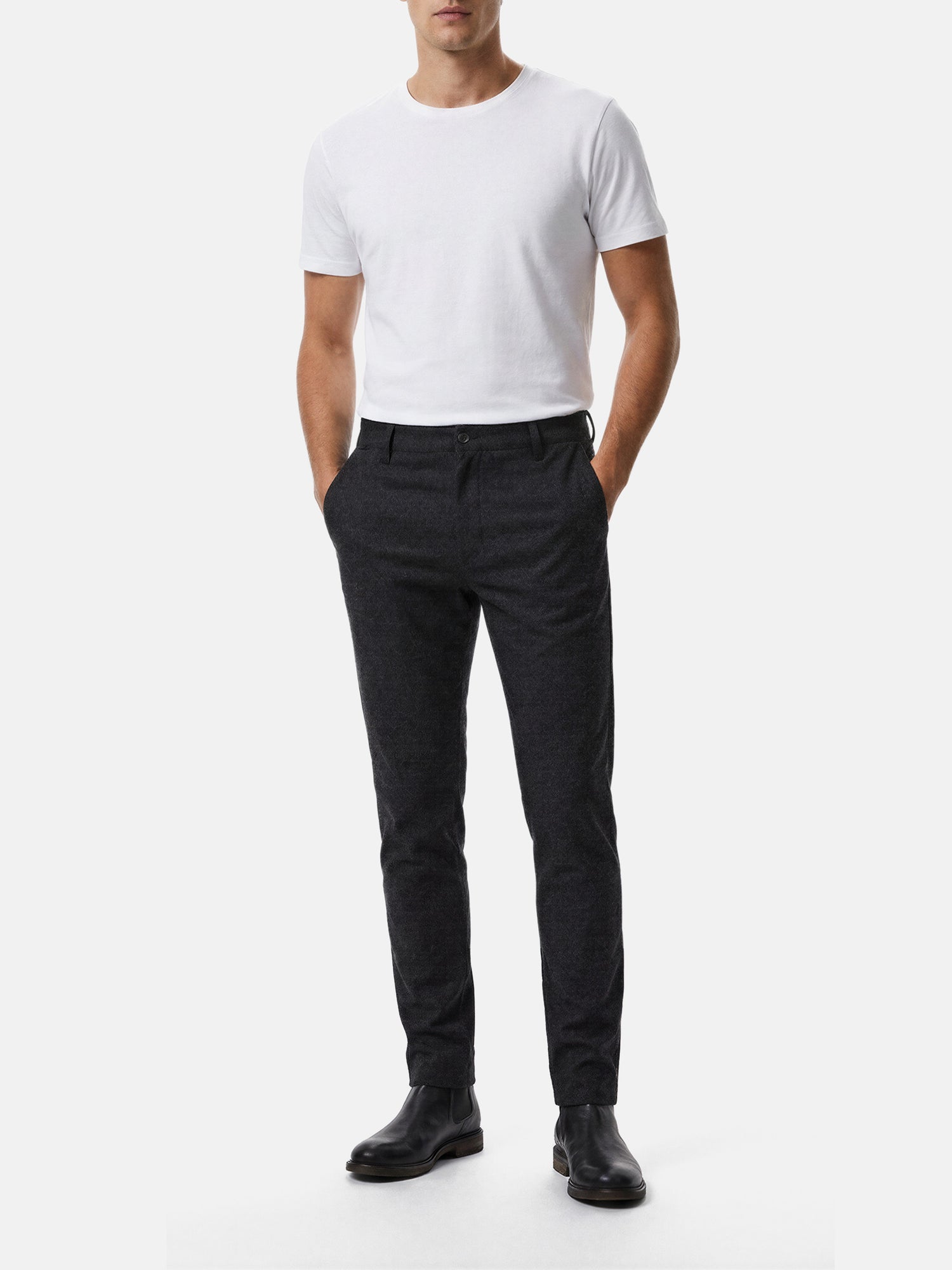 Model wearing dark grey men’s chino pants with slim fit, styled casually with white t-shirt.