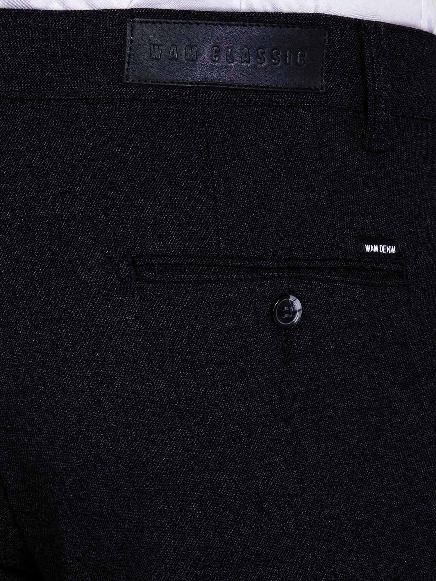 Close-up of dark navy chino trousers showing back pocket, button detail, and Wam Denim label.