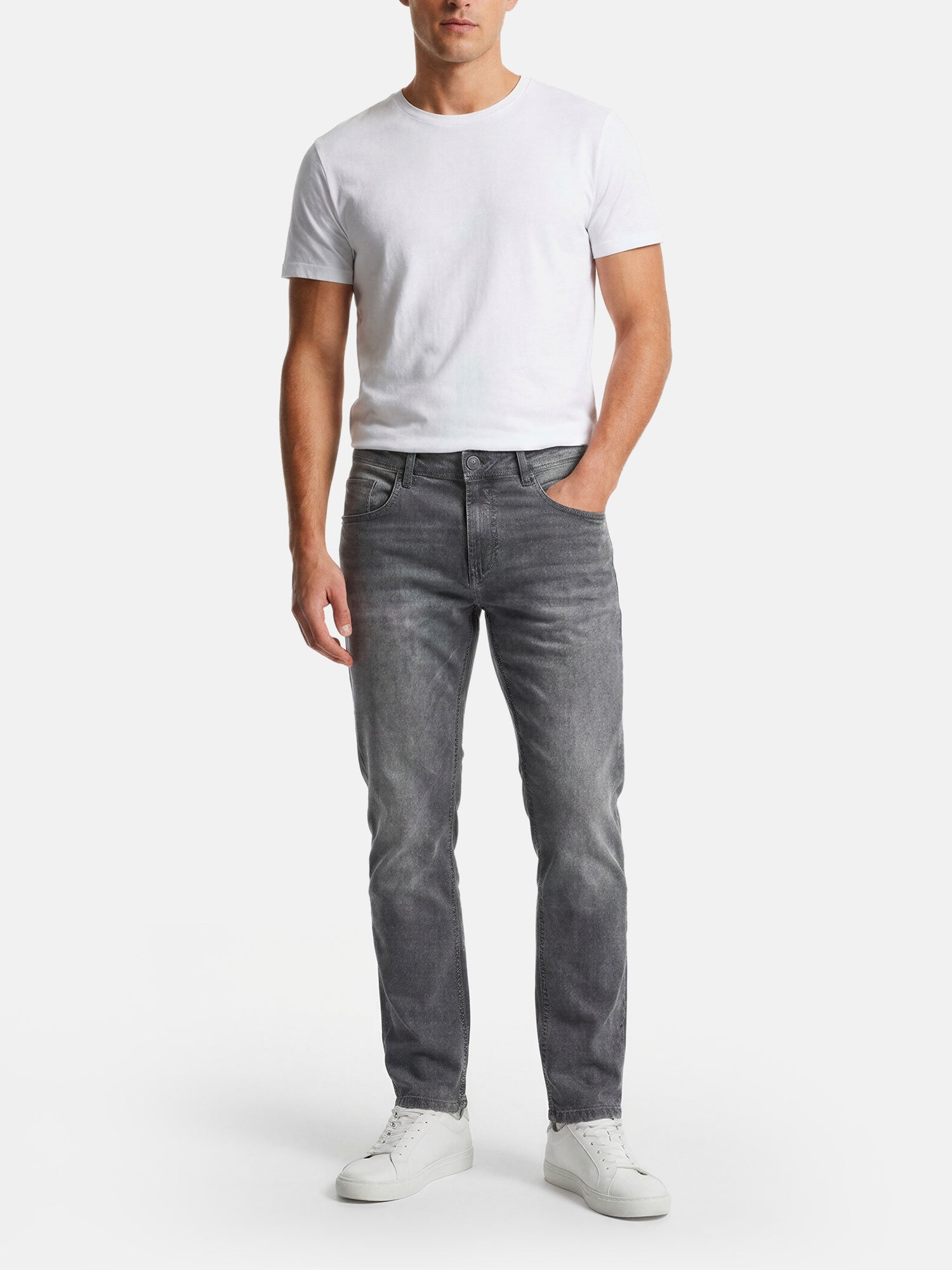 Model wearing slim-fit grey jeans styled with a white t-shirt and sneakers.